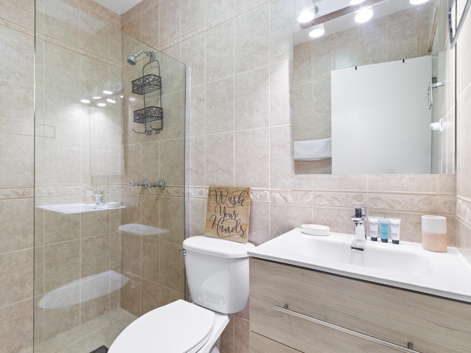 Classy Bathroom of the 2BR Home in Noord, Aruba - Neat and clean toilet seat - Availability of all bathroom amenities - Beautiful vanity with large size wall mirror - Elegant lighting - Stunning separate glass made shower area