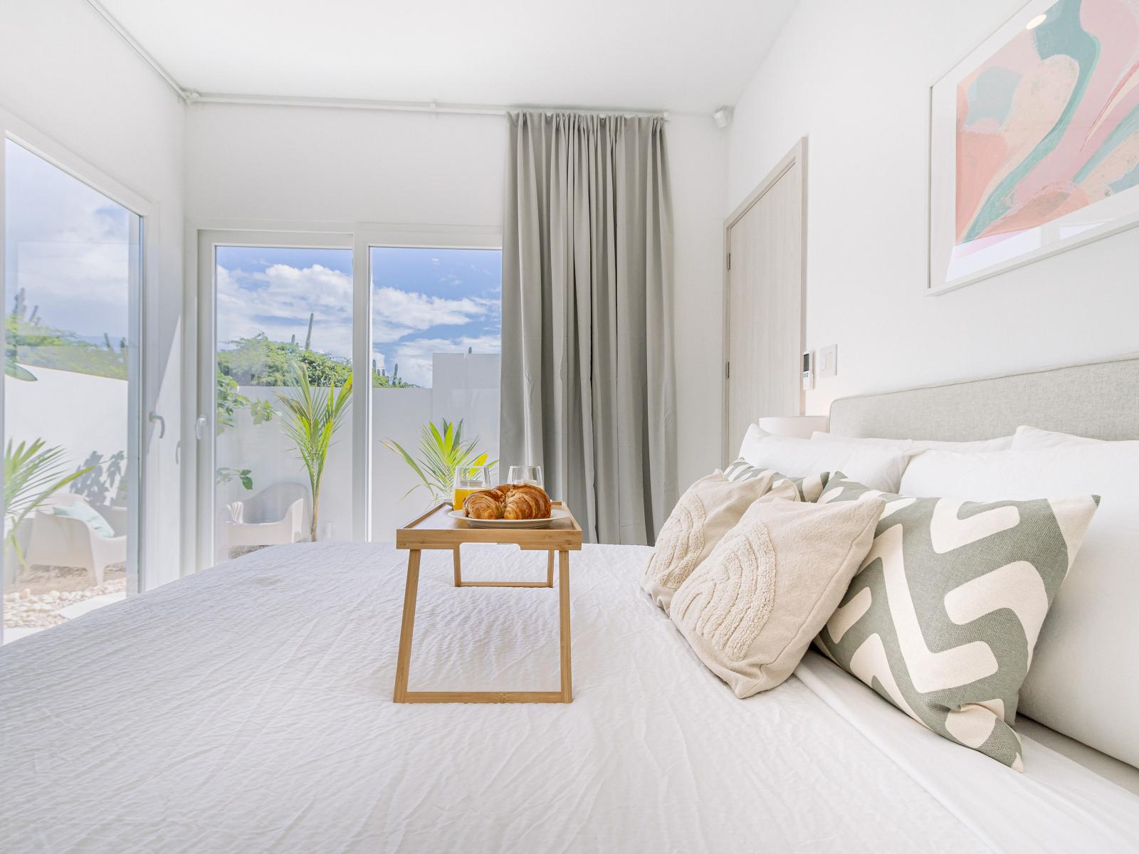 Eclat Bedroom of the Home in Oranjestad Aruba - Glass sliding doors that connect to the backyard - Cozy retreat with a plush bed, perfect for relaxation - Thoughtfully designed bedroom featuring functional and stylish furniture