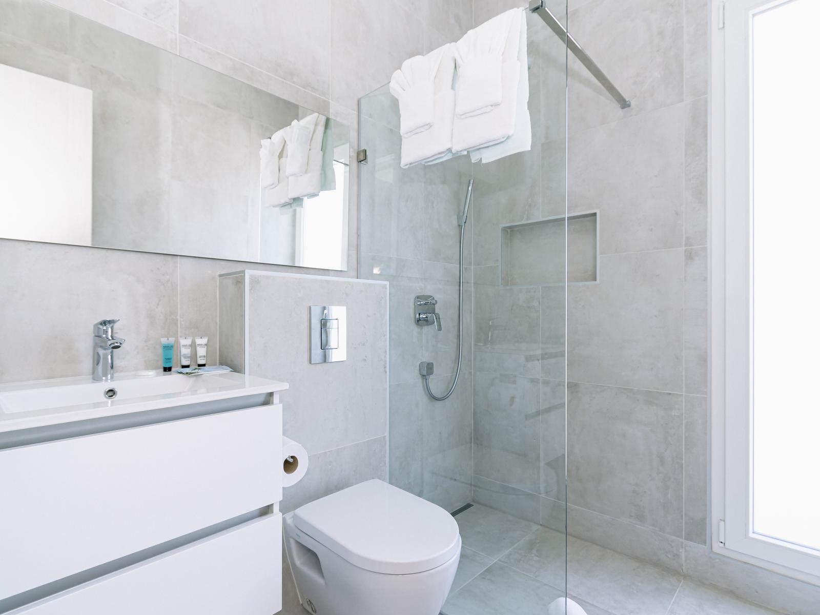 Enchanting Bathroom of the Home in Oranjestad Aruba - Lush Vanity with full size mirror - Walk-in Shower for modern feel - Harmonious blend of classic and contemporary elements