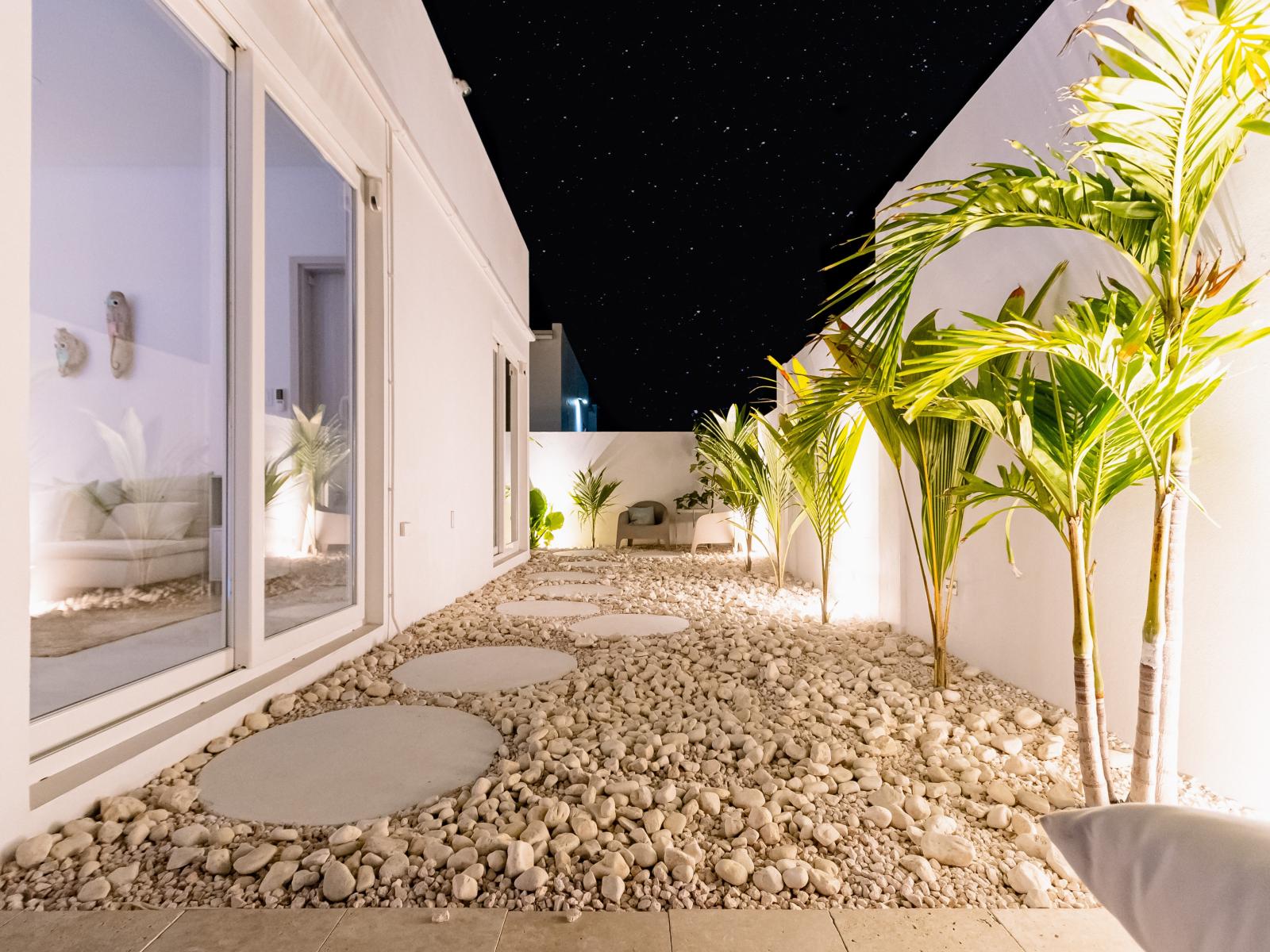 Pathway on the side of the home with round pavers to lead the way through the white Caribbean beach pebble stone layout - Tropical trees and plants increase the Vacation feel