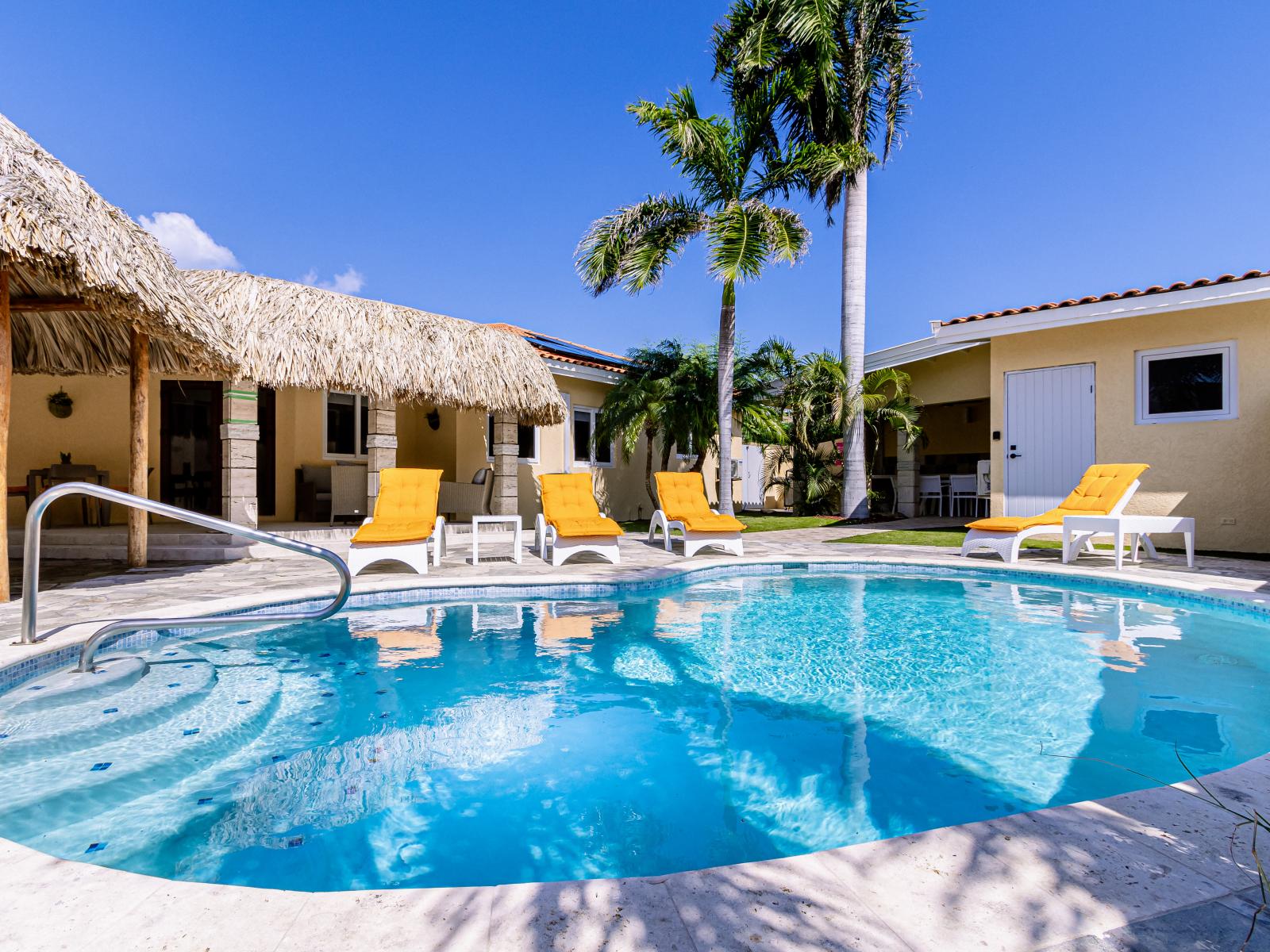 Amazing pool area of the Villa in Noord, Aruba - Lush and refreshing environment - Cosy beach chairs  - Beautiful sitting space under the umbrella shade - Completely sunbathed space - Experience the comfort at the best