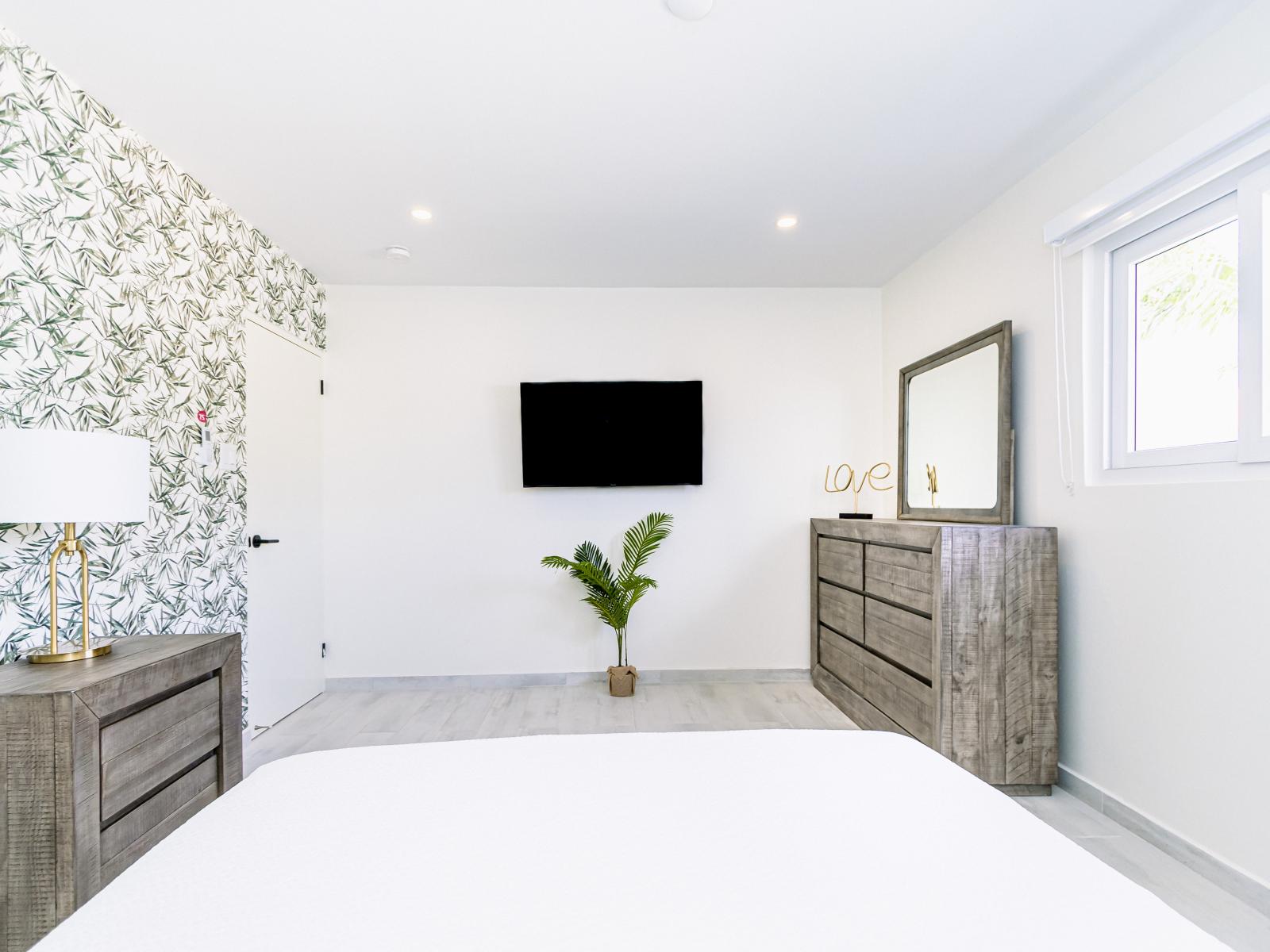 Indulge in Bedroom 2's luxurious comfort, featuring an attached bathroom and a captivating palm print backdrop that enhances the room's tropical charm.