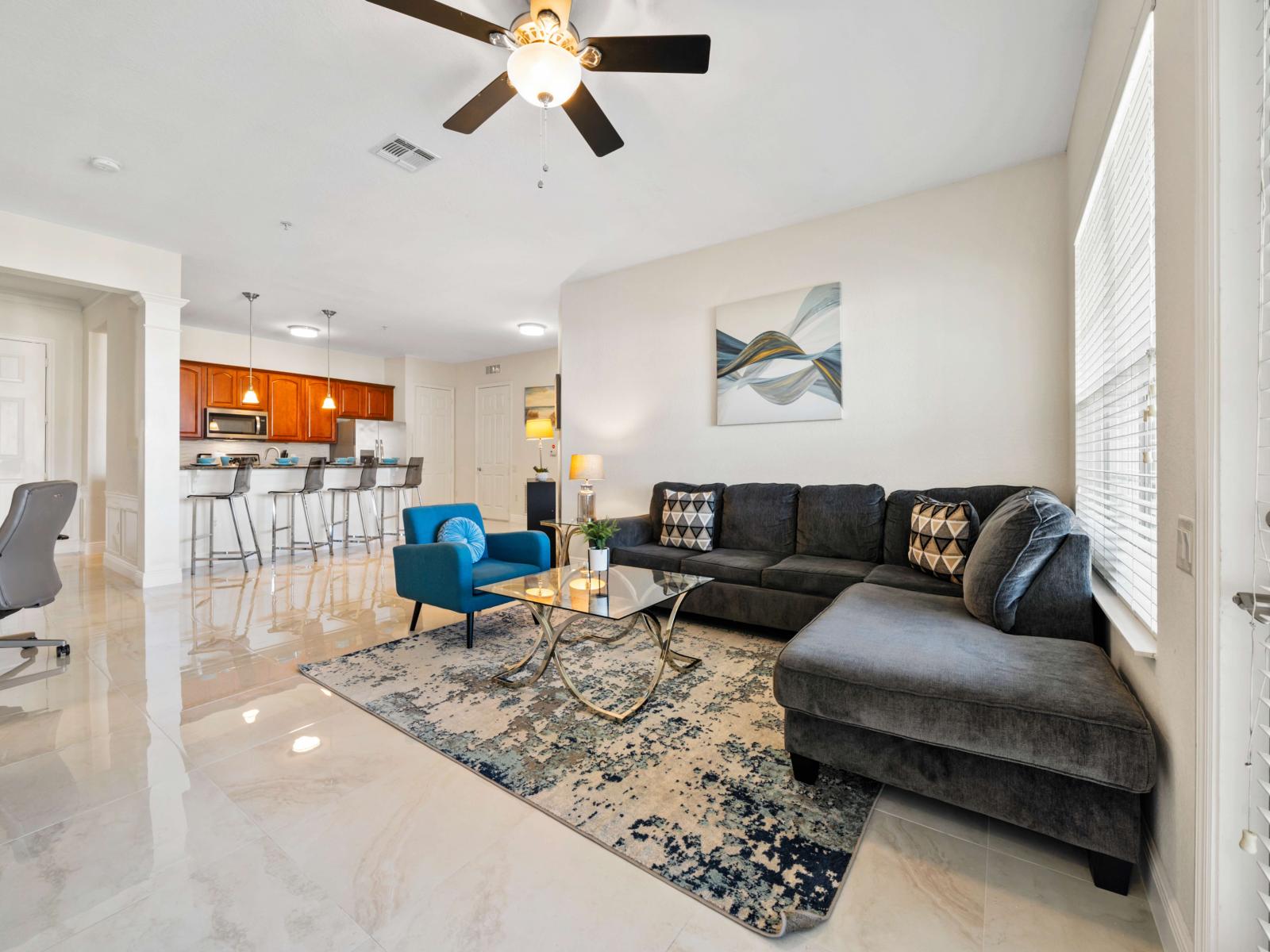 Living area with a large sofa, smart tv and ceiling fan