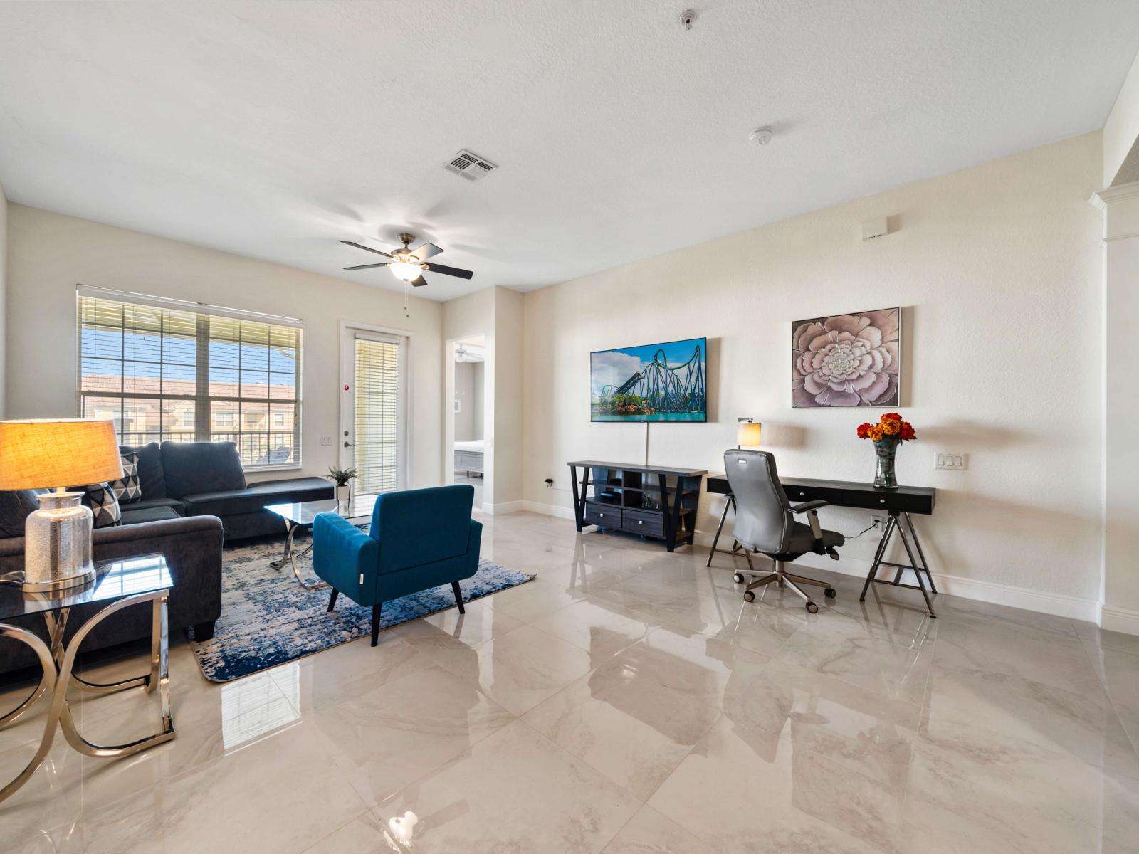 Living area with a large sofa, smart tv and ceiling fan