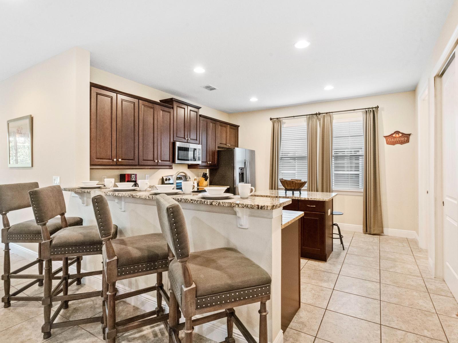 Stunning Kitchen of the Home in Kissimmee Florida - Breakfast Bar with Stylish High Chairs - Elegant and coordinated color palette for a cohesive look - Functional island for additional workspace