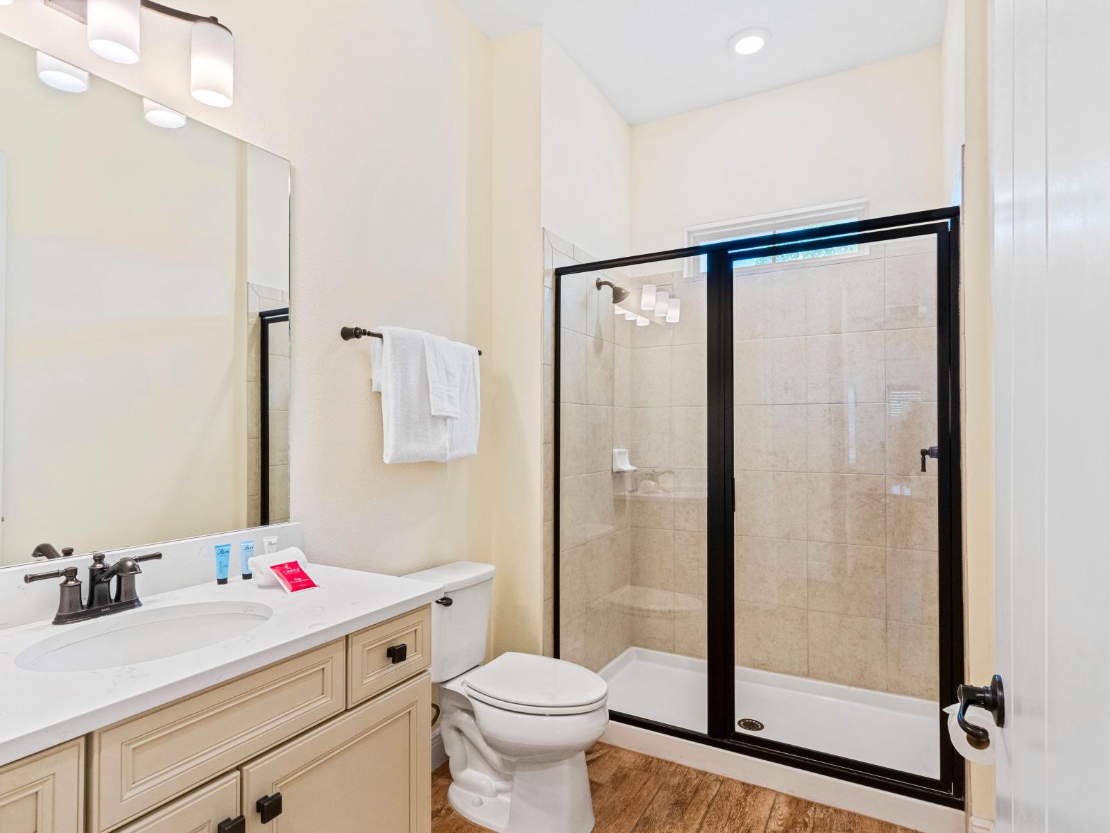 Bright bathroom of the cottage in Kissimmee Florida - Indulge in a refreshing experience with a walk-in shower stall - Chic vanity with large mirror and upscale lighting