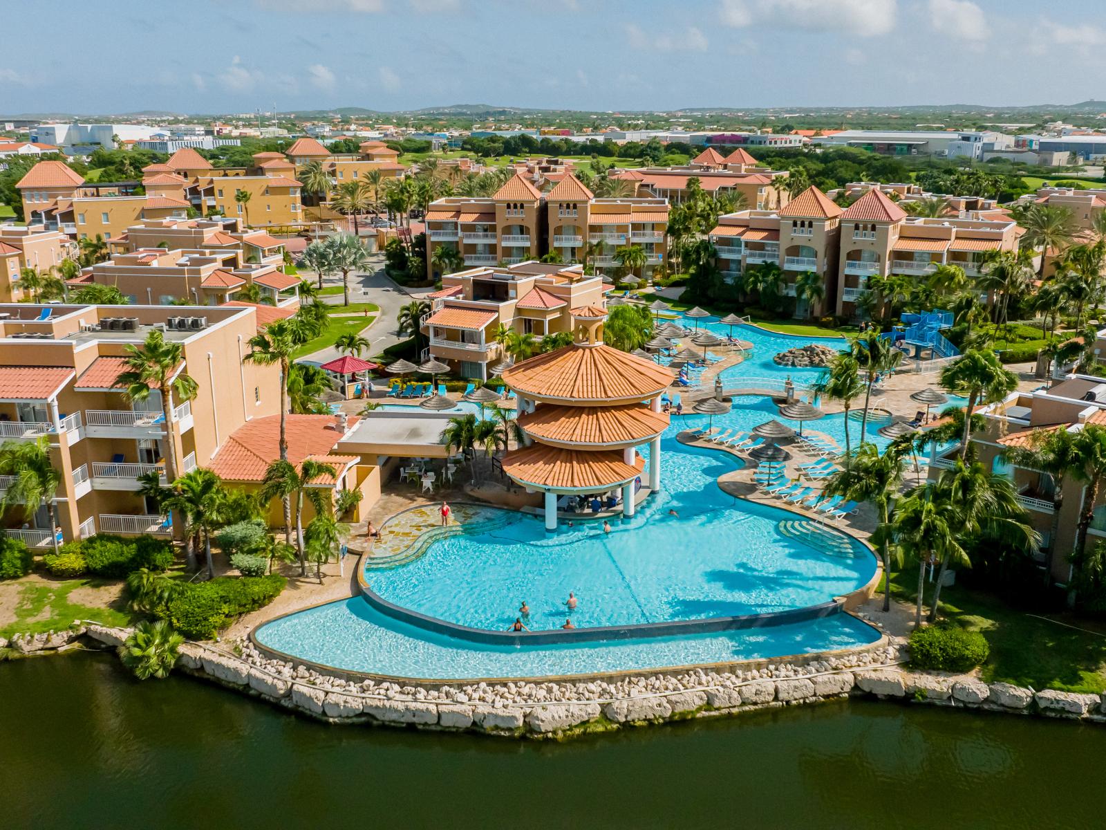 Lush pool area of Divi Village pool in Noord, Aruba - Cozy beach chairs and neat and clean towels available - Beautiful sitting under umbrella shades - Beautiful view - Superbly designed pool area - Refreshing Environment - Vibrant Atmosphere