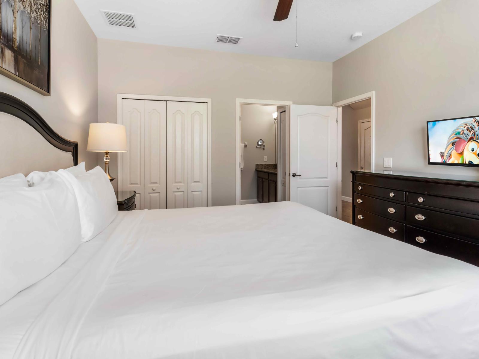 The bedroom with a TV offers guests a serene sanctuary for relaxation and rejuvenation. With its crisp white decor and modern amenities, including a TV for entertainment.