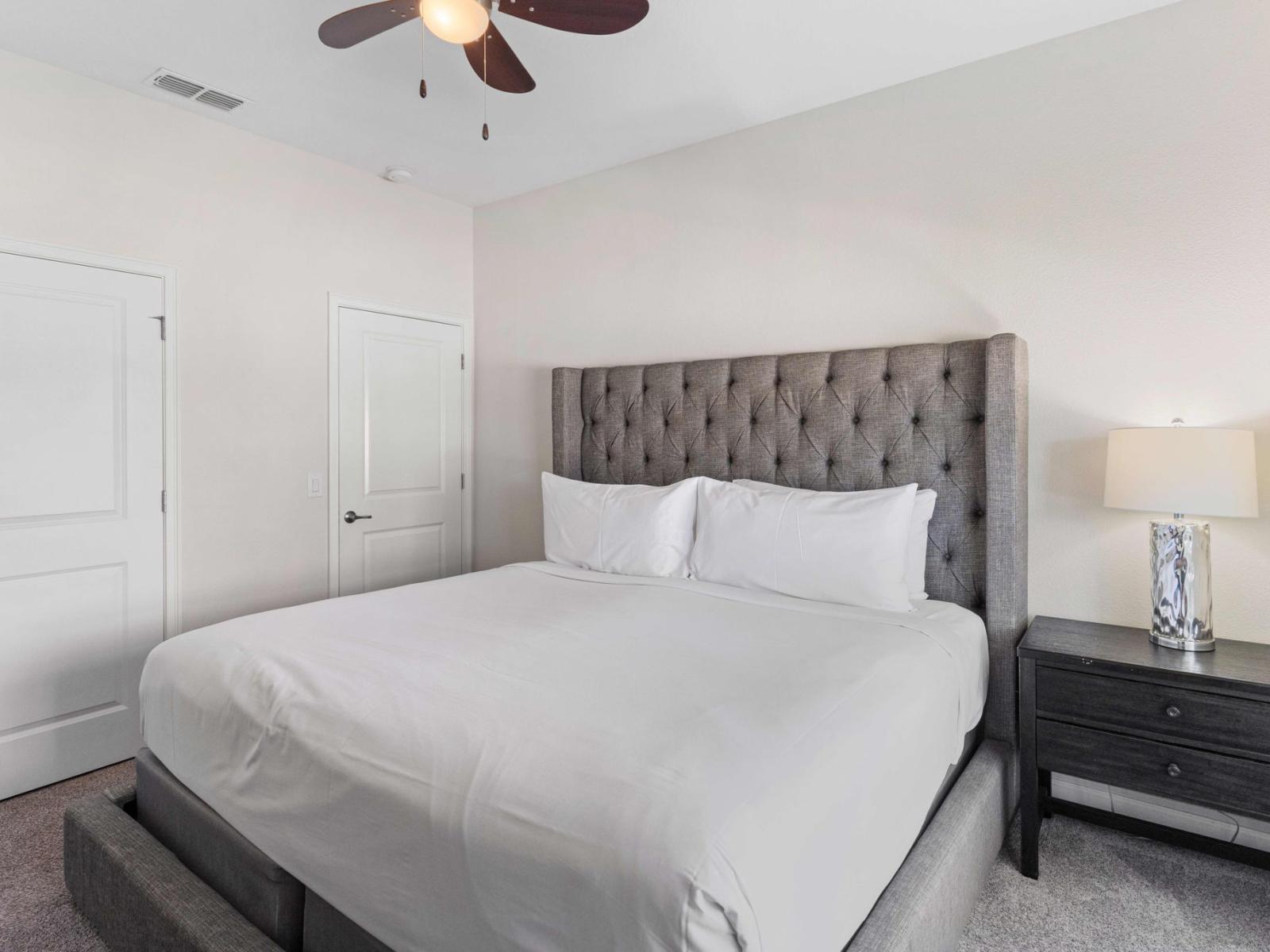 Relax in Style: Bedroom 1 Welcomes You with a King-Size Bed and Ceiling Fan for Added Comfort.