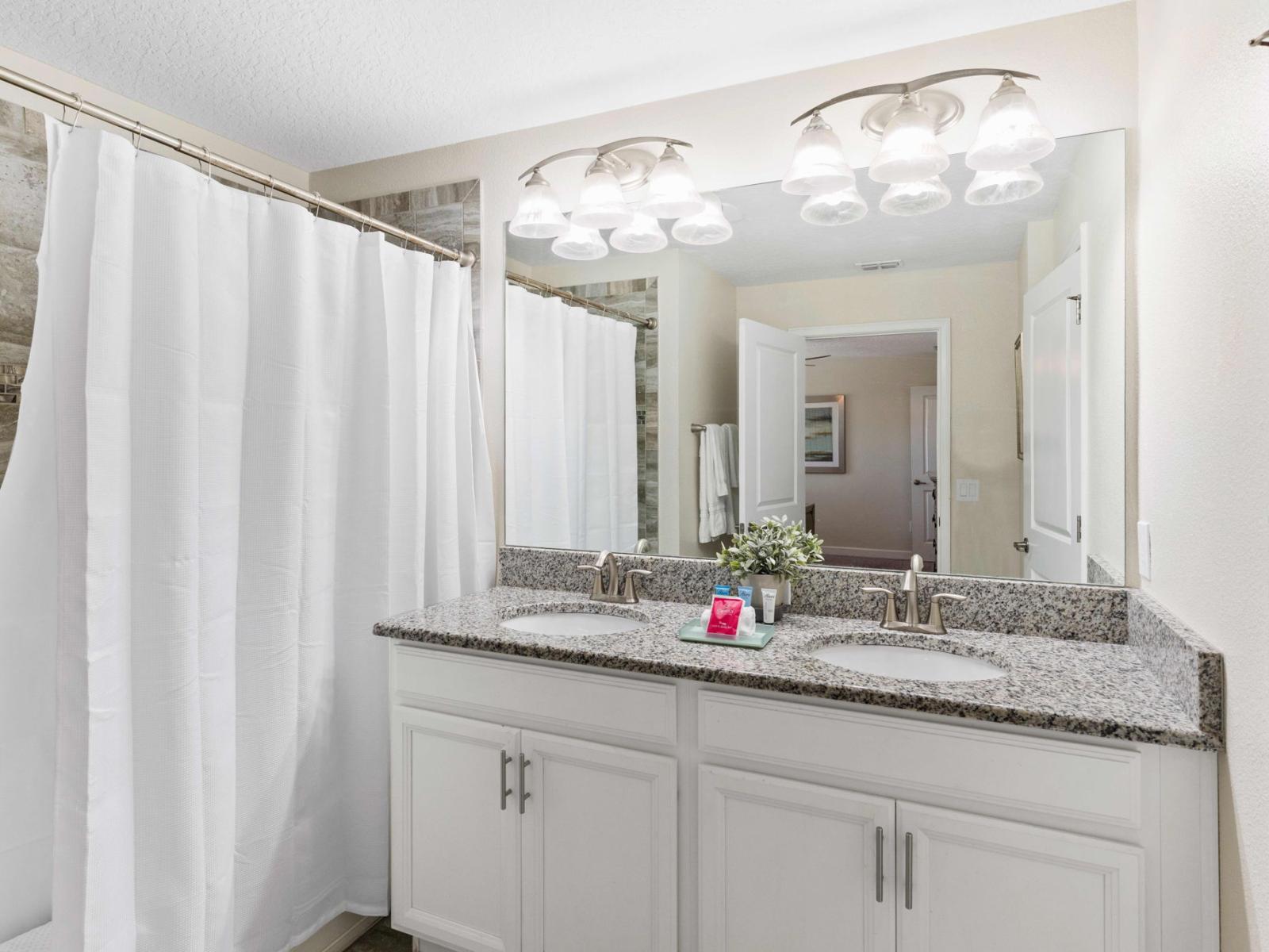 Polished bathroom of the town house in Kissimmee Florida - Sleek dual vanity with large mirror and upscale lighting - Bathtub and shower combo - Sophisticated color palette creating a serene ambiance