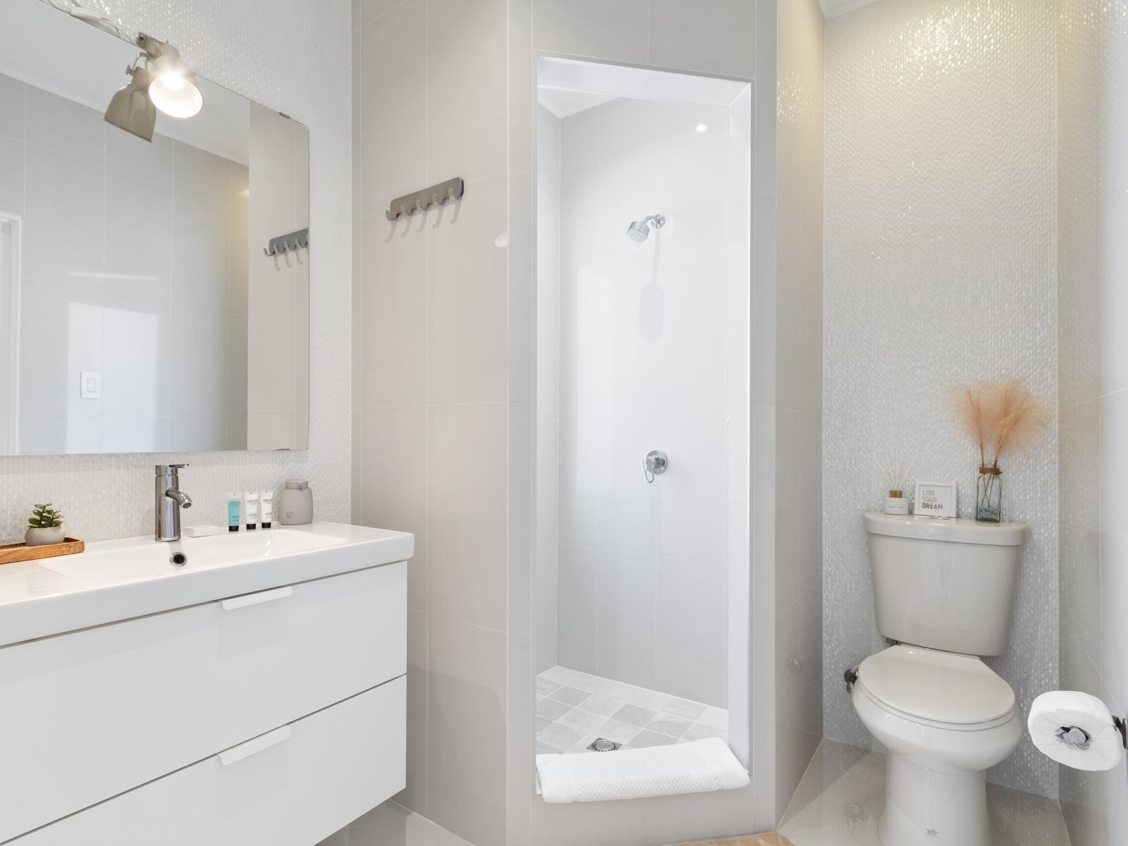 High-end Bathroom of the villa in Noord Aruba - Beautiful Vanity with large size wall mirror - Sufficient storage space - Neat and clean toilet seat - Availability of all bathroom amenities - Stunning cabin shower area