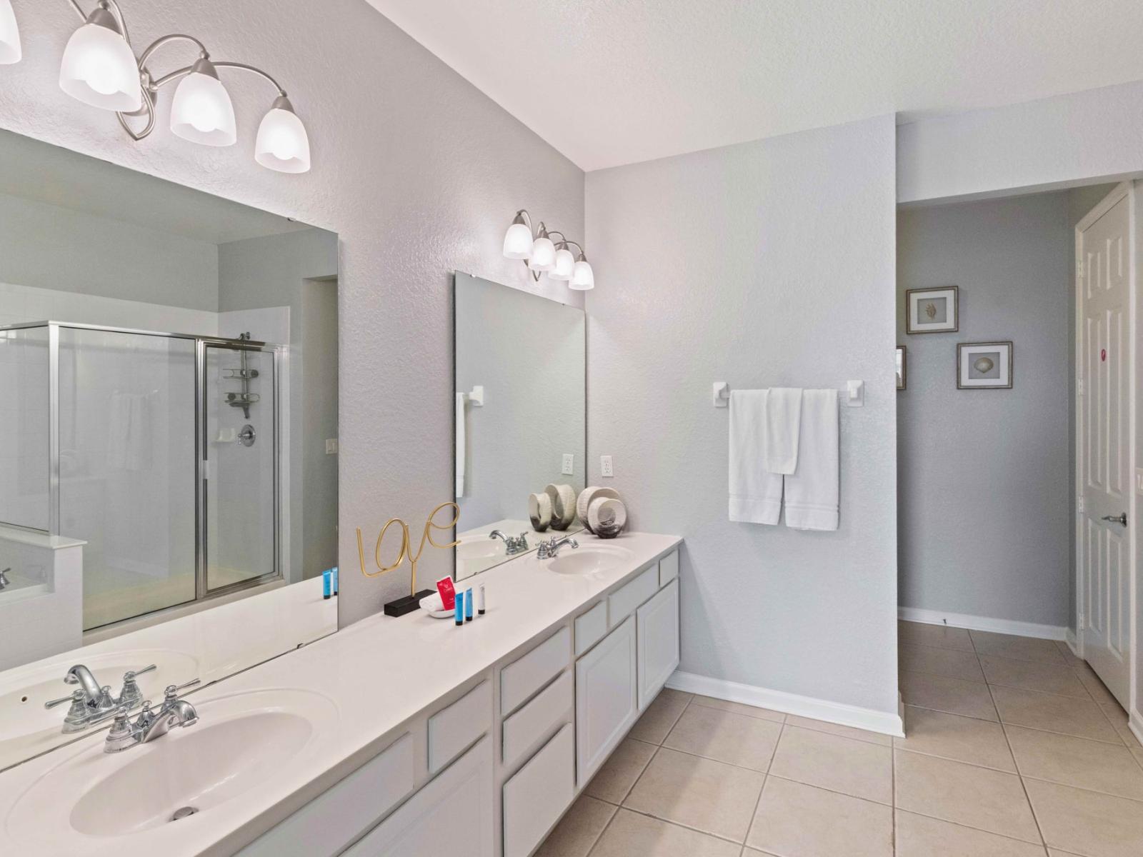 High-end Main bathroom of the condo in Orlando - Glamorous twin sink vanity with large wall mirrors and lamps - Fresh and cozy towels available including all bathroom amenities - neat and clean toilet seat