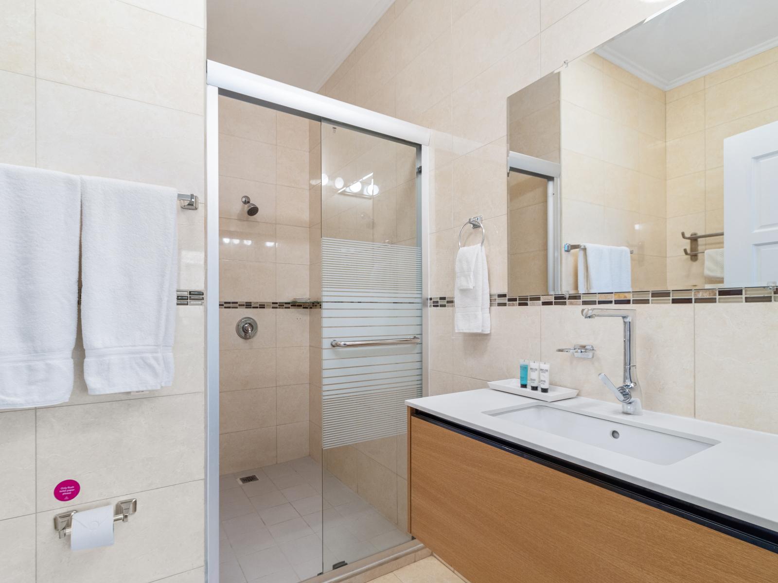 lavish Bathroom of the 2BR Condo in Noord Aruba - Walk-in shower - Chic vanity with upscale lighting - Elegant bathroom with luxurious fixtures and finishes