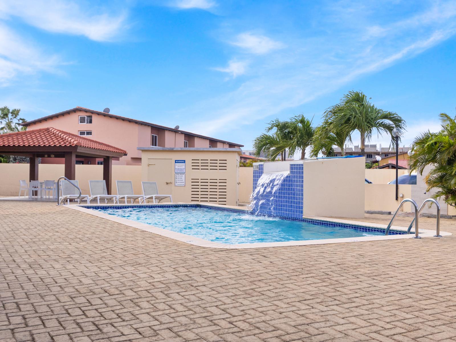 Refreshing Pool Area of the 2BR Condo in Noord Aruba - Beautiful Waterfall Pool - Crystal-clear pool for refreshing dips - Experience ultimate relaxation in our poolside paradise