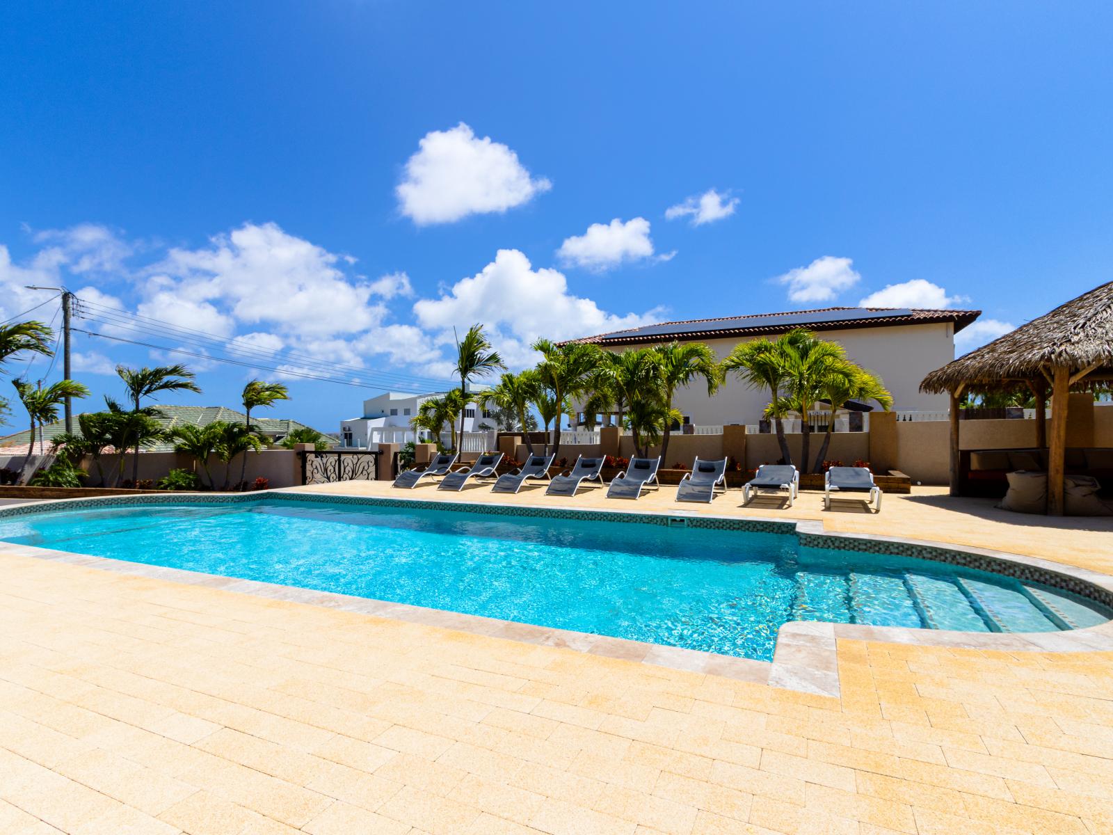 Enjoy the lap pool of this Villa with multiple chairs for guests to lie on and with a gazebo for a nice shade on a sunny day