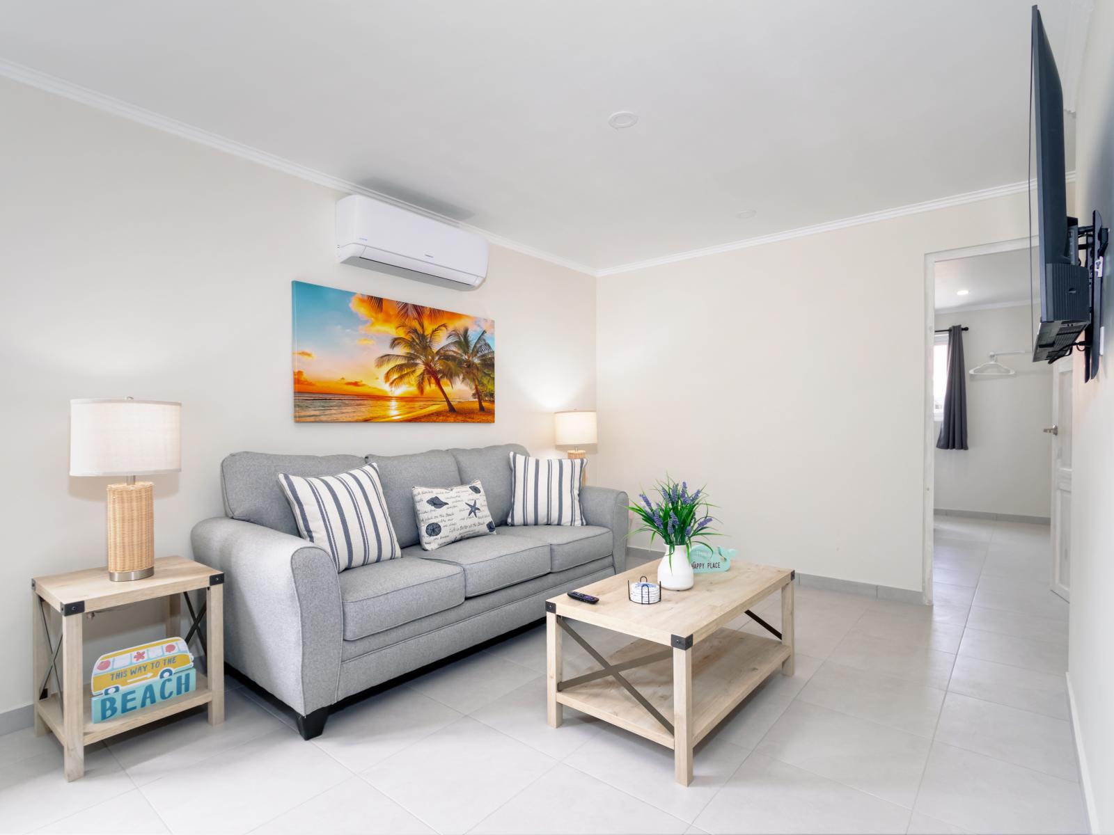 Luxurious Living Area of 2-BR Condo in Noord Aruba - Cozy sofas  - Potted plants for a refreshing and lively ambiance - Open Kitchen - High Chairs available - Smart TV and Netflix