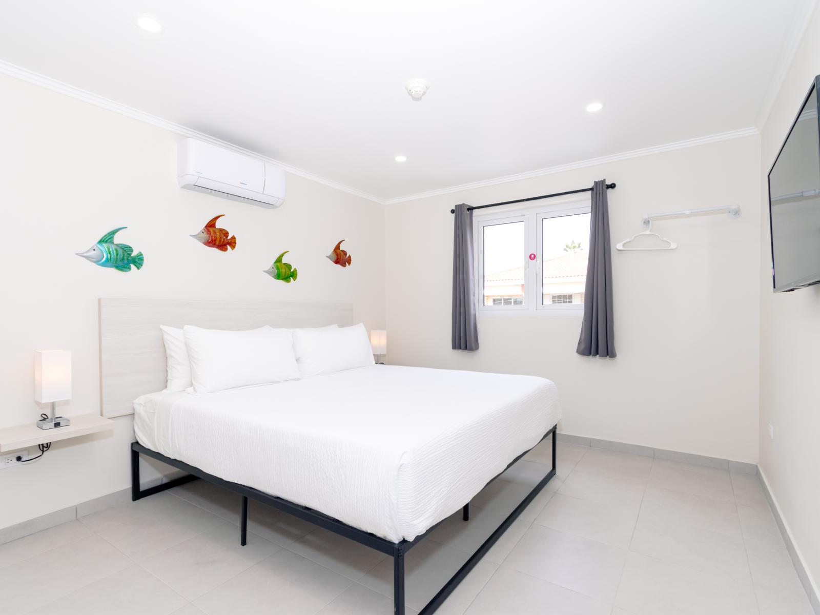 Charming Bedroom of the 2-BR Condo in Noord Aruba - Smart TV and Netflix - Bright and airy bedroom with windows for natural illumination - King Bed with comfy and cozy feel - Modern and stylish decor that complements the space