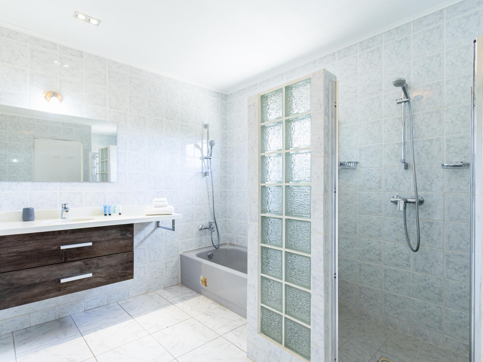 Polished Bathroom of the Villa in Noord Aruba - Seamless design featuring a walk-in shower for a modern touch - Well-designed space with a focus on both aesthetics and functionality - Separate Bathtub  - Wooden Vanity with stylish look