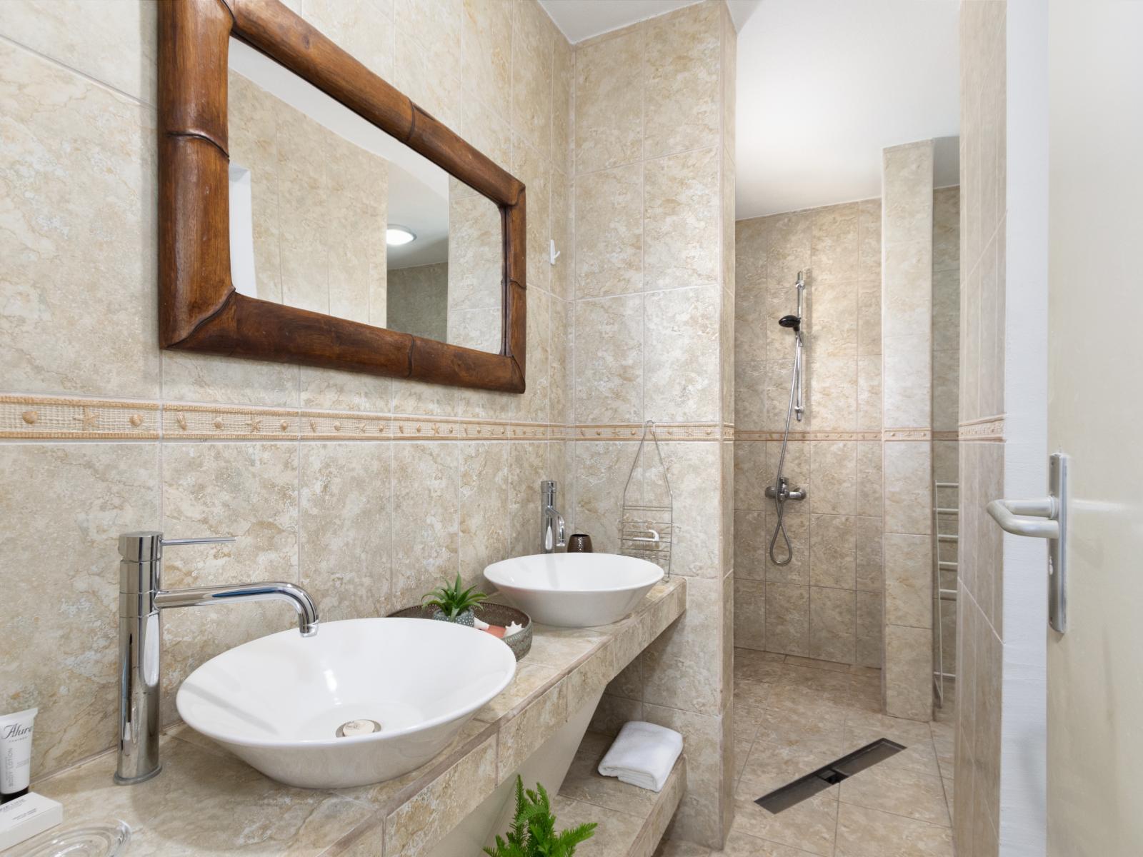 Palatial Bathroom of the 3BR house in Noord Aruba - Sophisticated color palette creating a serene ambiance - Ample natural light highlighting the elegant tilework - Seamless design featuring a walk-in shower for a modern touch