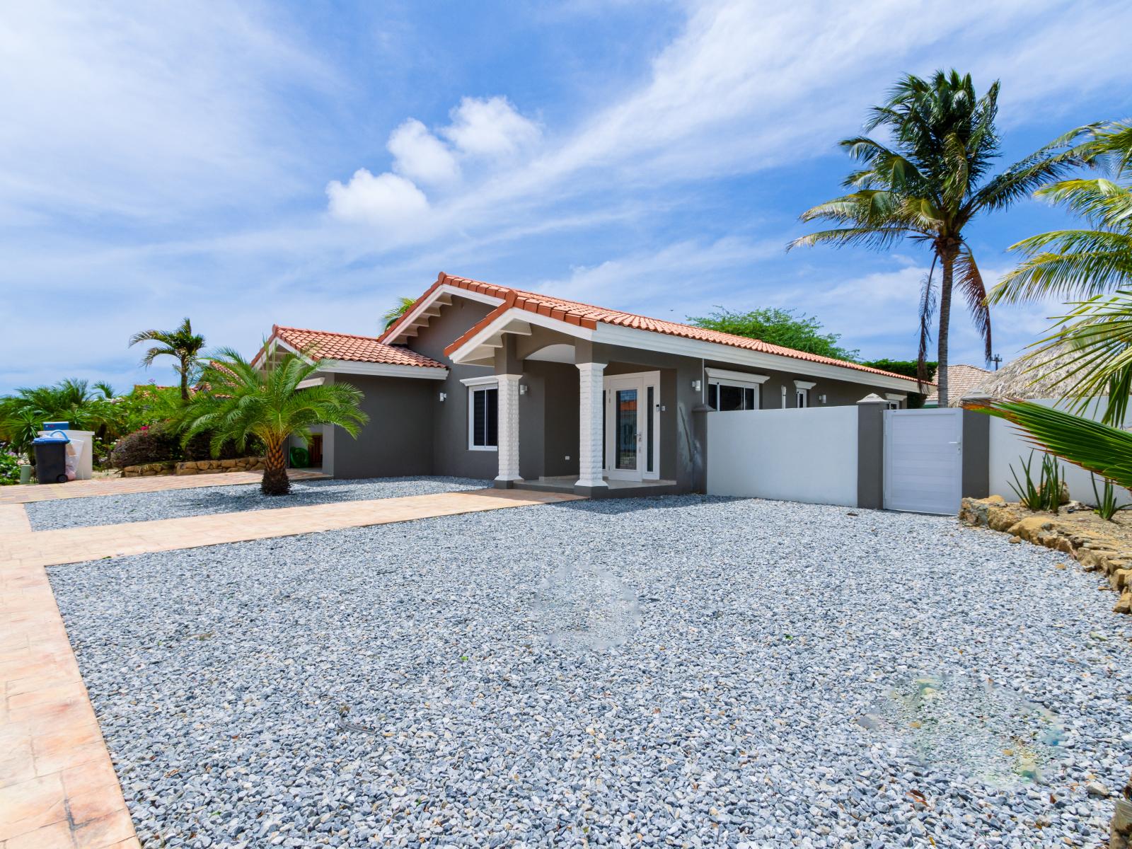 Inviting Entrance of the 3BR house in Noord Aruba - Palm trees and tropical plants enhance the vacation feel - Beautiful Home - Front of the home in nice street and neighborhood