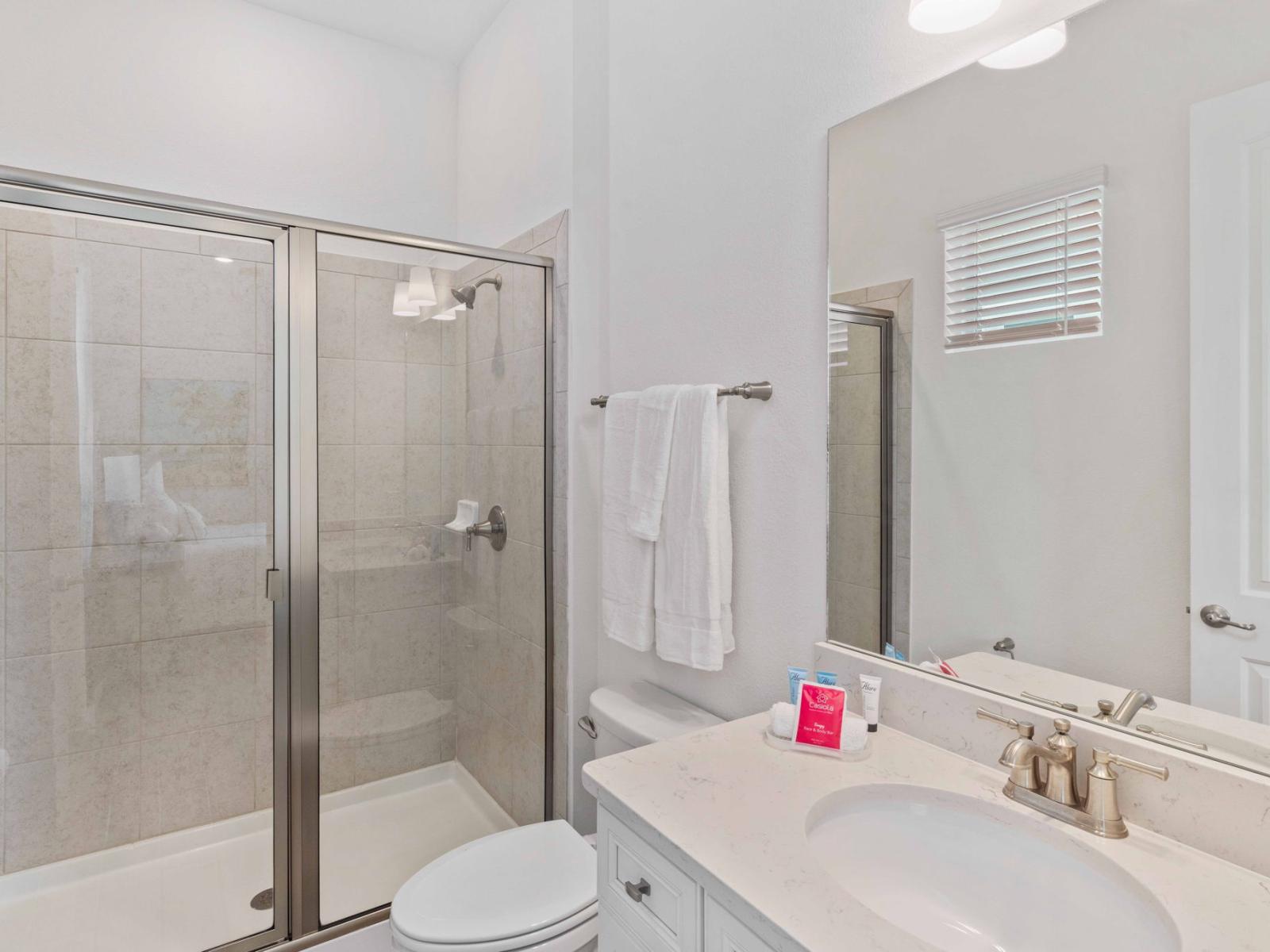 Polished bathroom of the townhouse in Reunion Florida - Glass-enclosed walk-in shower area - Chic vanity with large mirror - Clean space