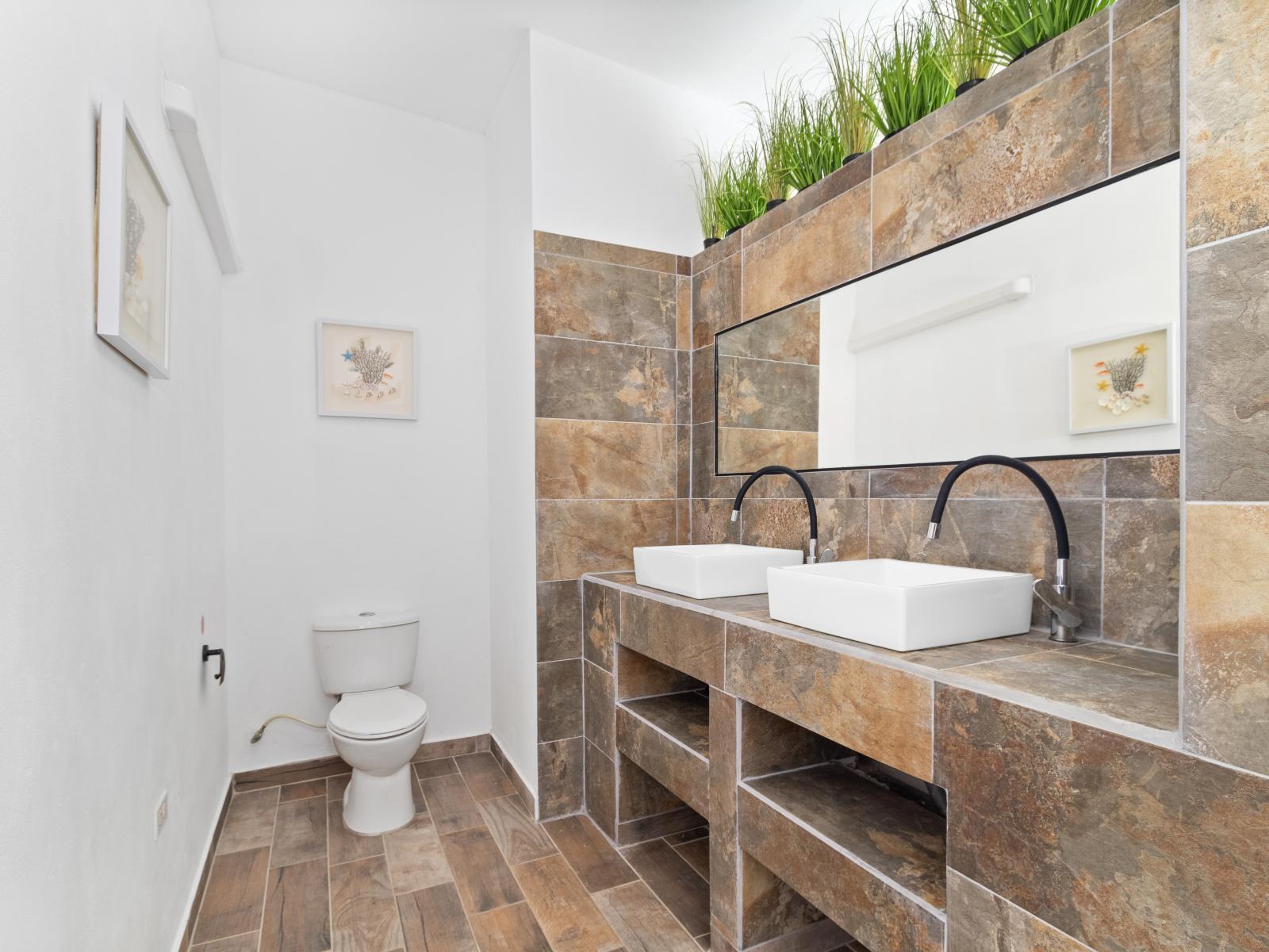 Luxe Bathroom of the home in Noord Aruba - Lush dual vanity - Potted plants for touch of nature - Contemporary fixtures for a touch of indulgence