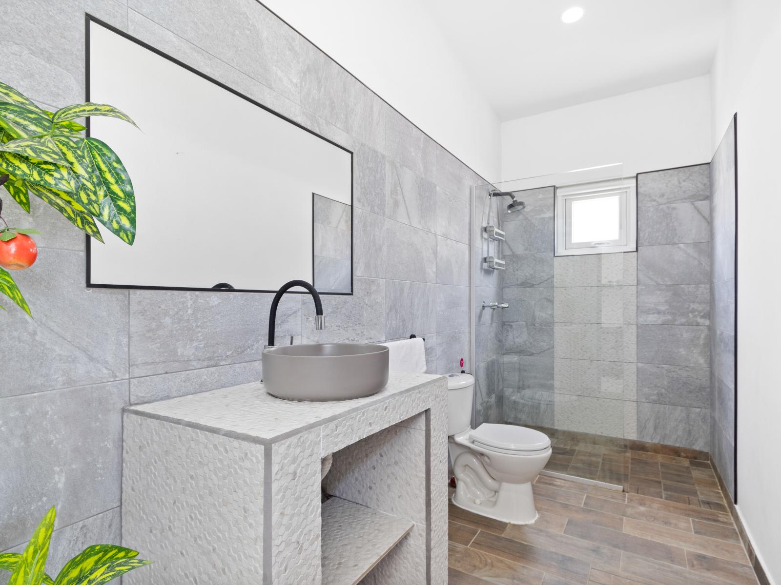 Lush Tiled Bathroom of the home in Noord Aruba - Chic design featuring a sleek vanity and upscale lighting - Walk in Shower area - Sophisticated color palette creating a serene ambiance