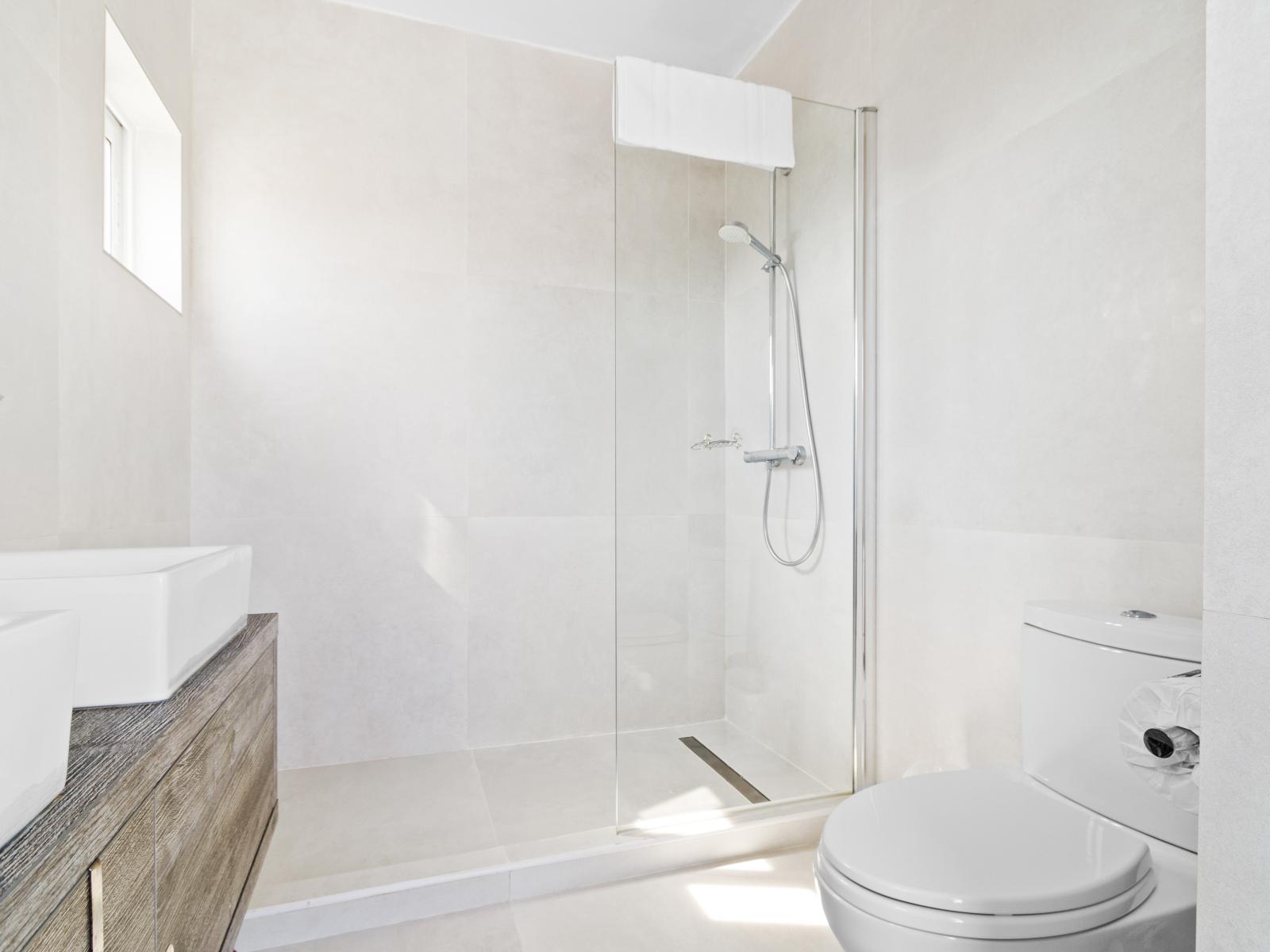 Gorgeous Bathroom of the vacation home in Santa Cruz Aruba - Well-lit space with strategically placed mirrors for a spacious feel - Contemporary fixtures for a touch of indulgence - Seamless design featuring a glass-enclosed shower