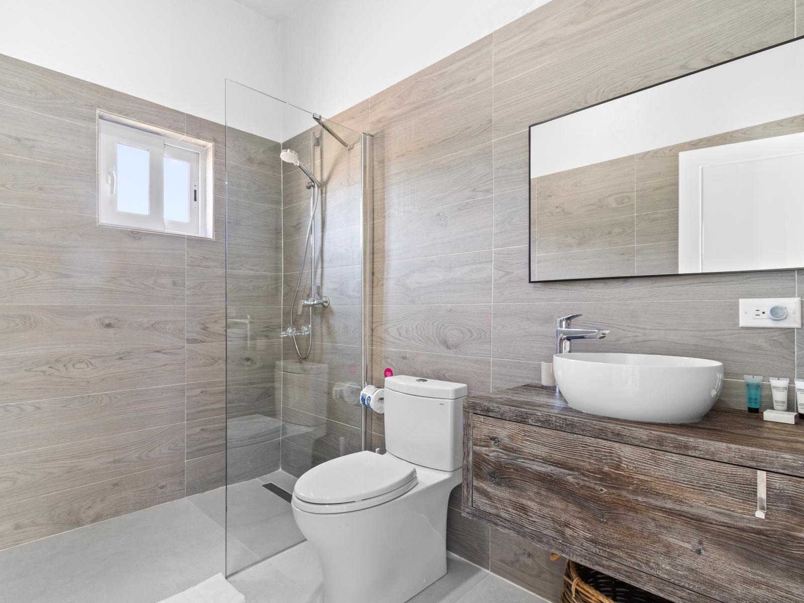 Tiled Bathroom of the vacation home in Aruba - Stylish Vanity with large mirror - Walk in shower - Elegant bathroom with luxurious fixtures and finishes