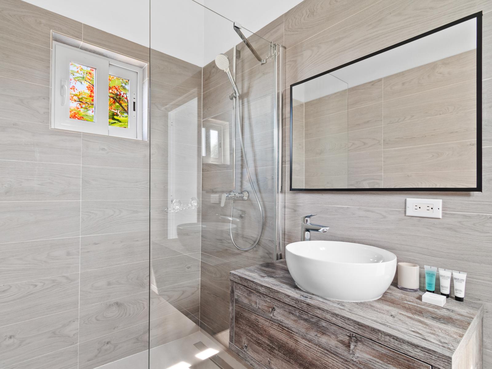 Bathroom 3 features a contemporary shower and a large mirror, blending convenience with style for a revitalizing and functional experience.