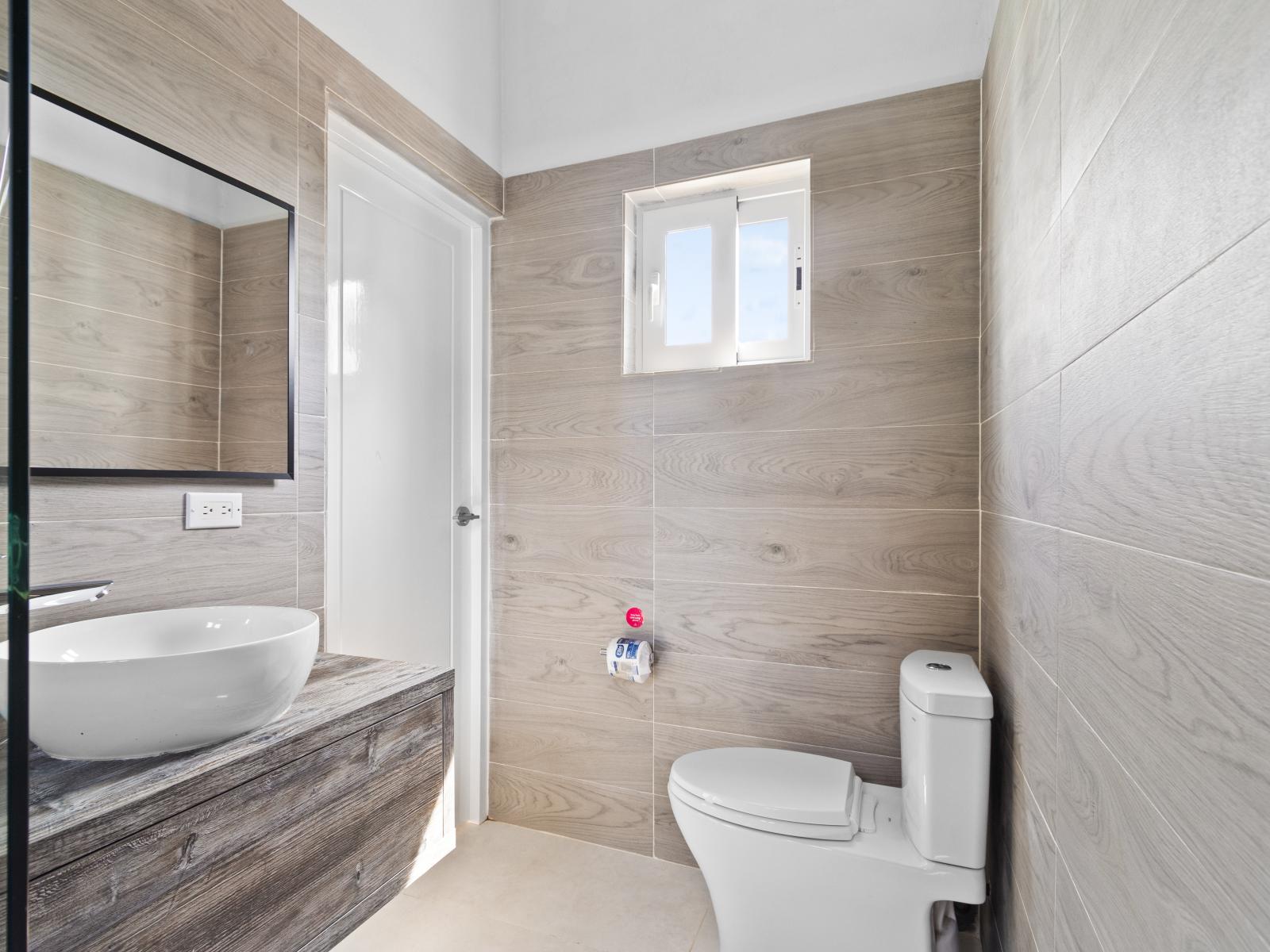 Experience Bathroom 3, featuring a stylish sink and hygienic toilet in a well-organized space with all essentials for your comfort and convenience.