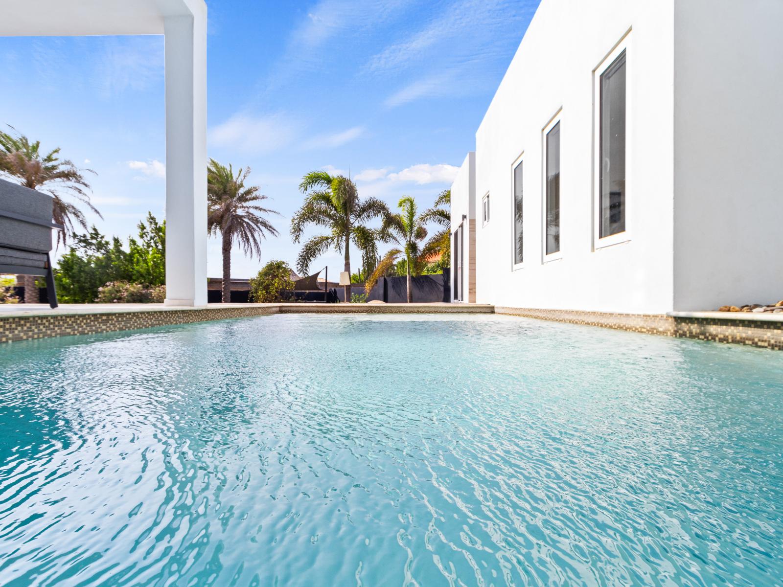 Crystal-clear pool water glistening under the sun, inviting a refreshing dip and relaxation.