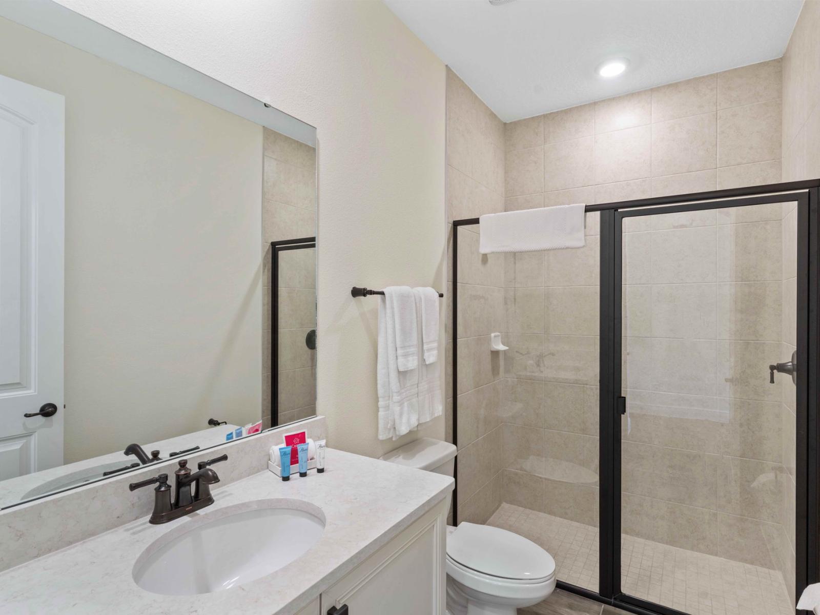 Bright bathroom of the cottage in Kissimmee Florida - Spacious glass-enclosed shower stall - Lush vanity with large mirror - Inviting bathroom with a soothing color palette for a tranquil feel