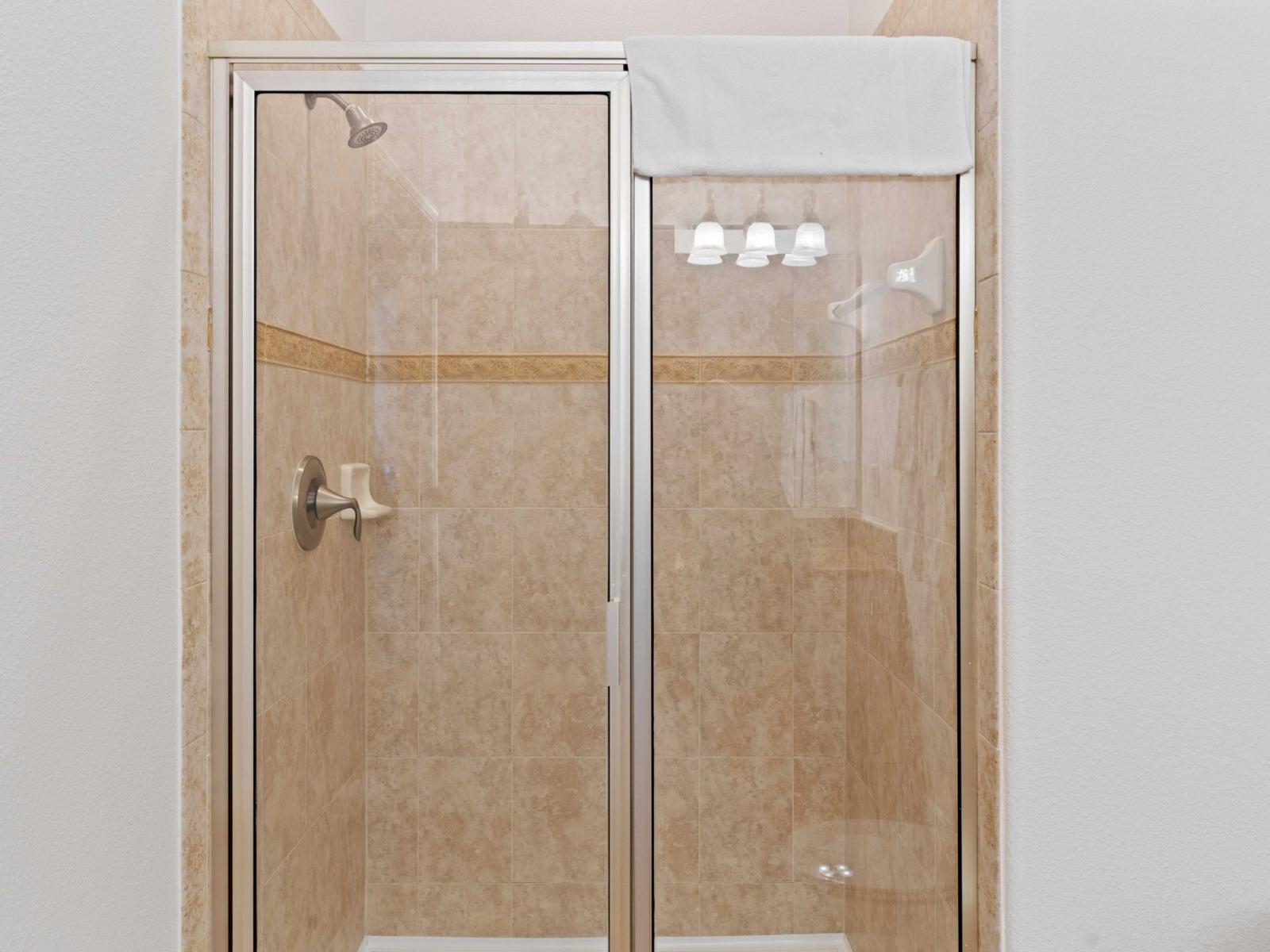 Tiled walk-in shower area of the townhouse in Kissimmee Florida - Glass-enclosed stall for modern feel - Meticulous design, from elegant tiles to faucets