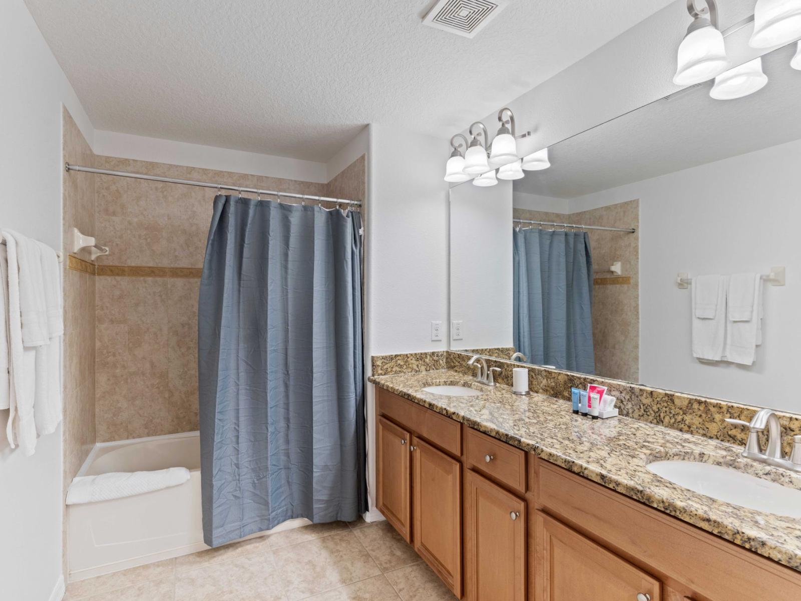 Relaxing bathroom  of the townhouse in Kissimmee Florida - Features a convenient bathtub and shower combination - Chic dual vanity with large mirror - Upscale lighting