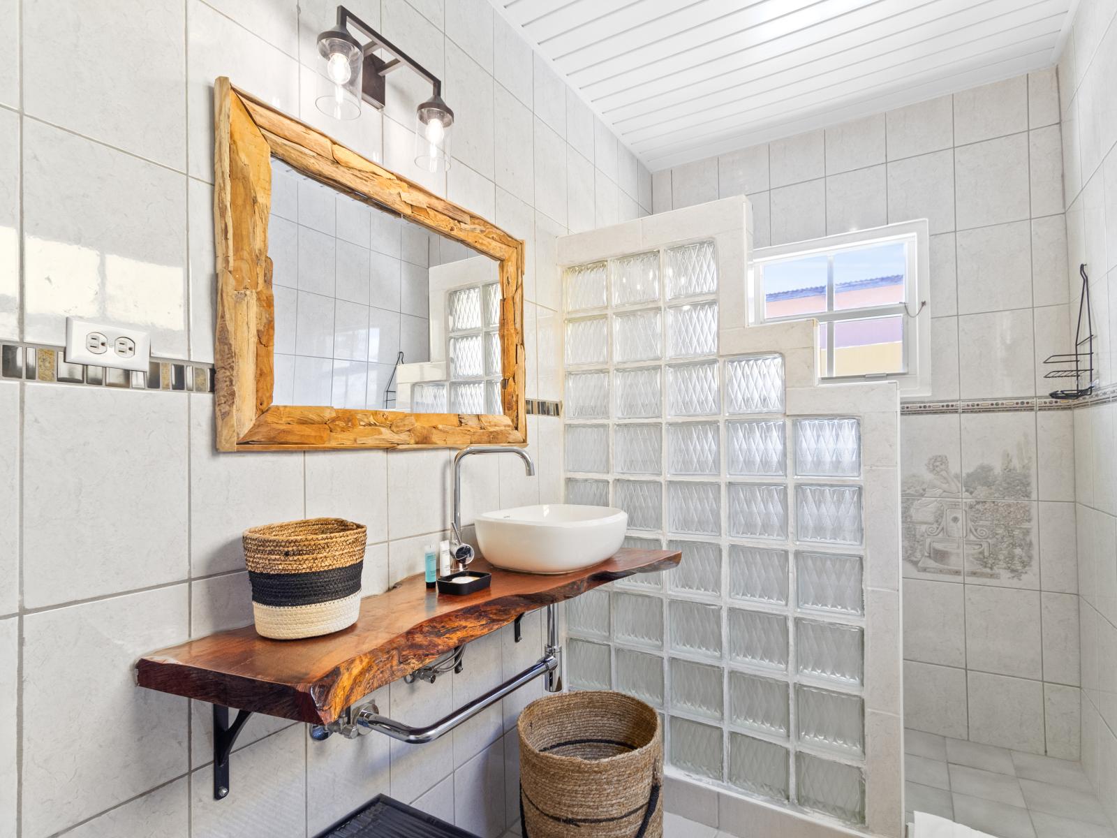 Posh Bathroom of the 3BR House in Noord Aruba - Walk-in shower area - Chic Vanity with large mirror - Sophisticated color palette creating a serene ambiance