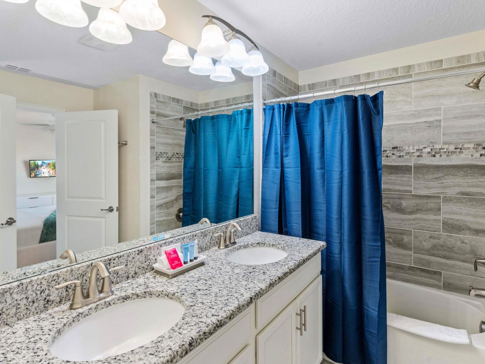 Sleek and Modern Oasis: Step into a sleek and modern oasis in our bathroom, complete with a vanity mirror, two sinks, and a luxurious walk-in shower-tub for your ultimate relaxation.