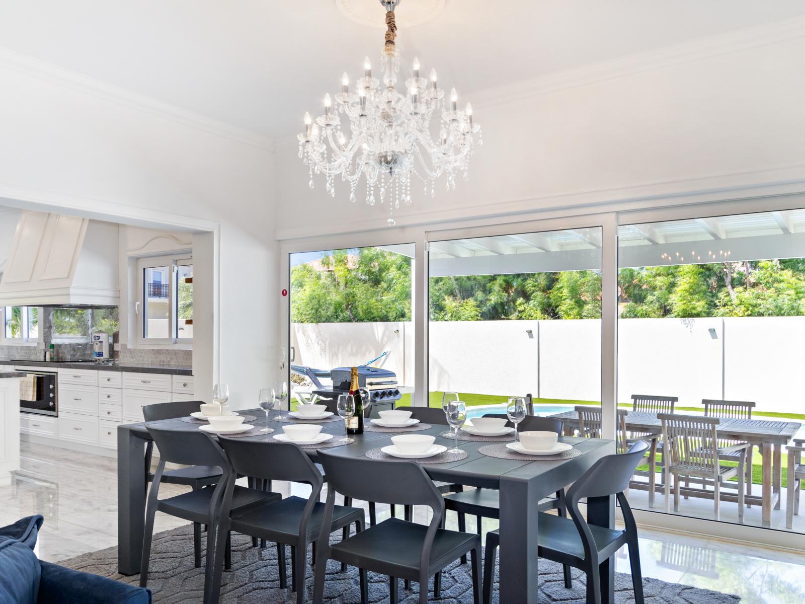 An indoor dining table offering a scenic view of the pool and BBQ area, making it the perfect spot for enjoying meals and relaxation.