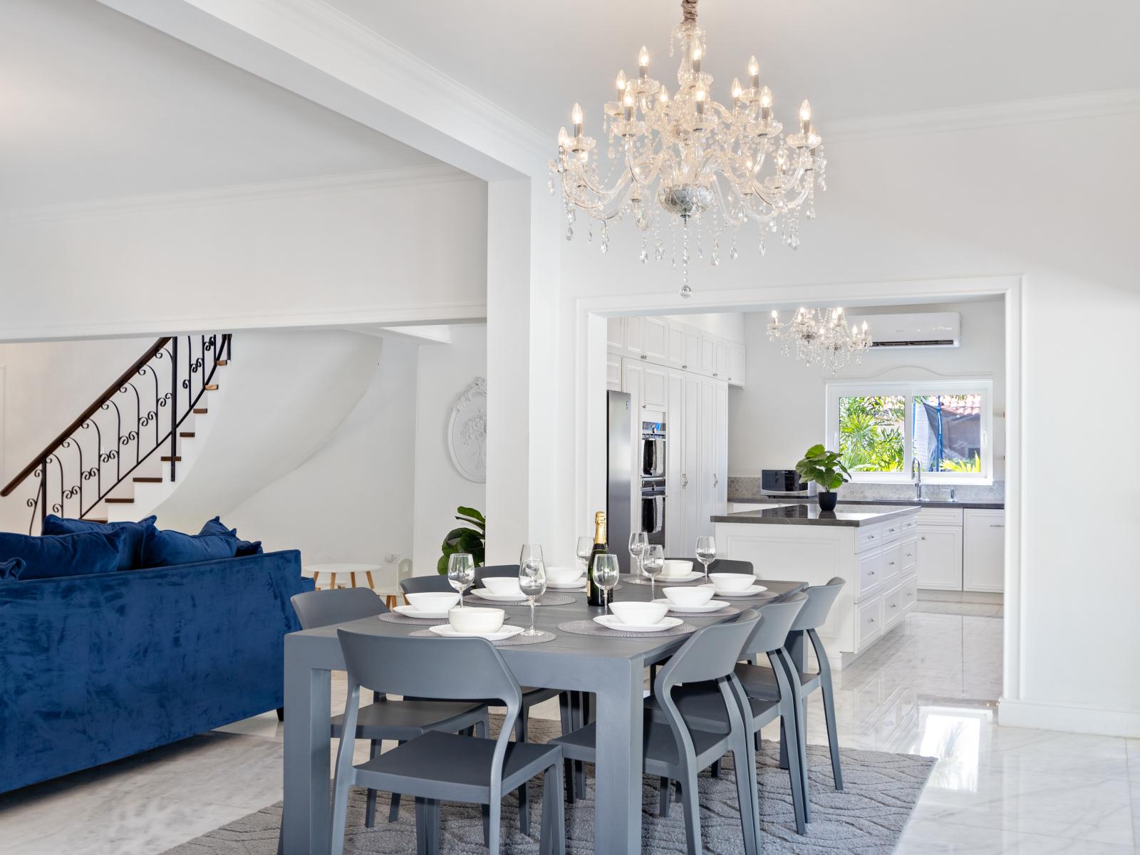 A beautiful and chic chandelier hangs above a dining table perfectly suited for eight, enhancing the elegance of the dining room.