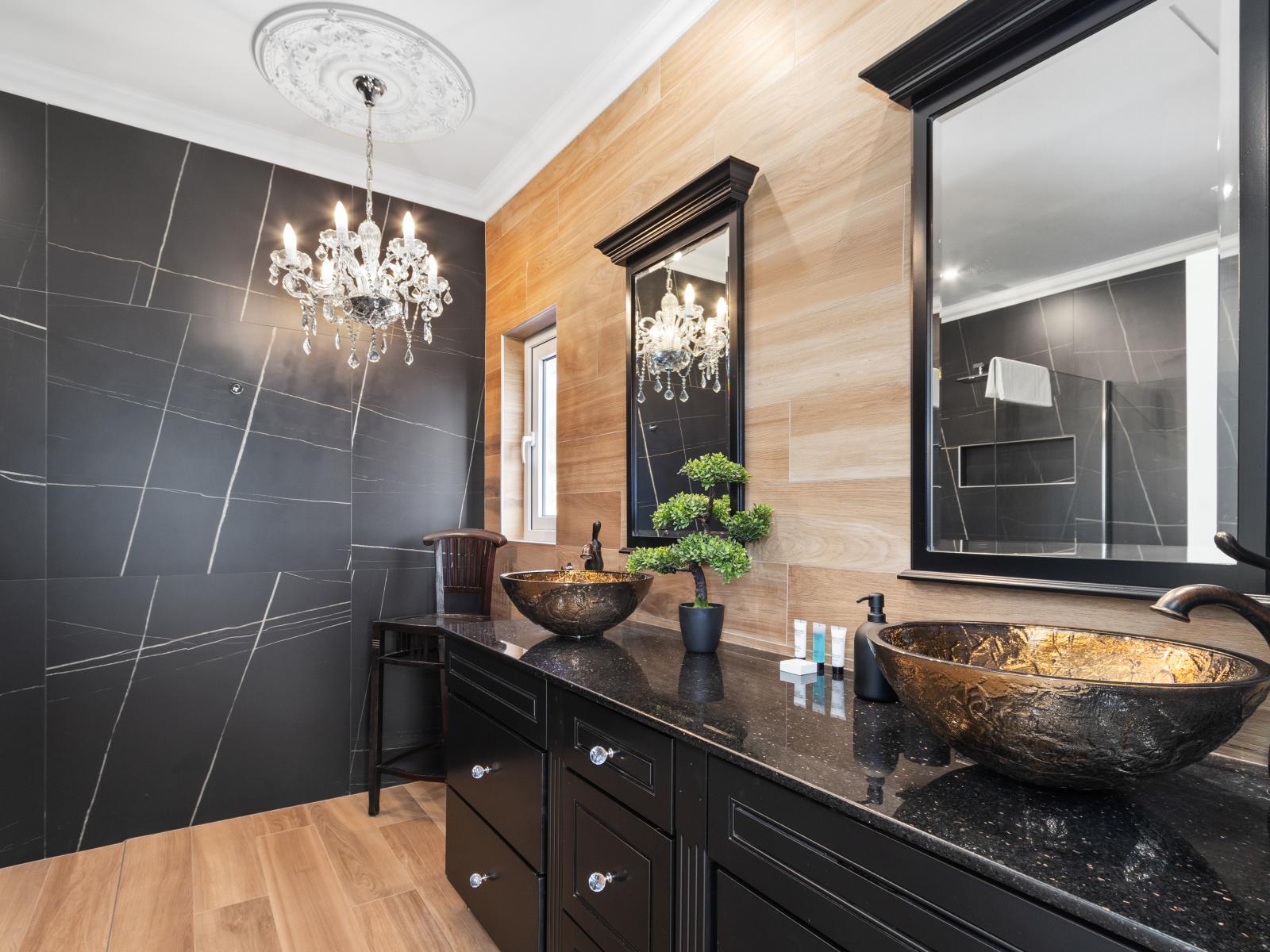 A modern bathroom featuring an elegant chandelier and double sinks adding a touch of luxury .