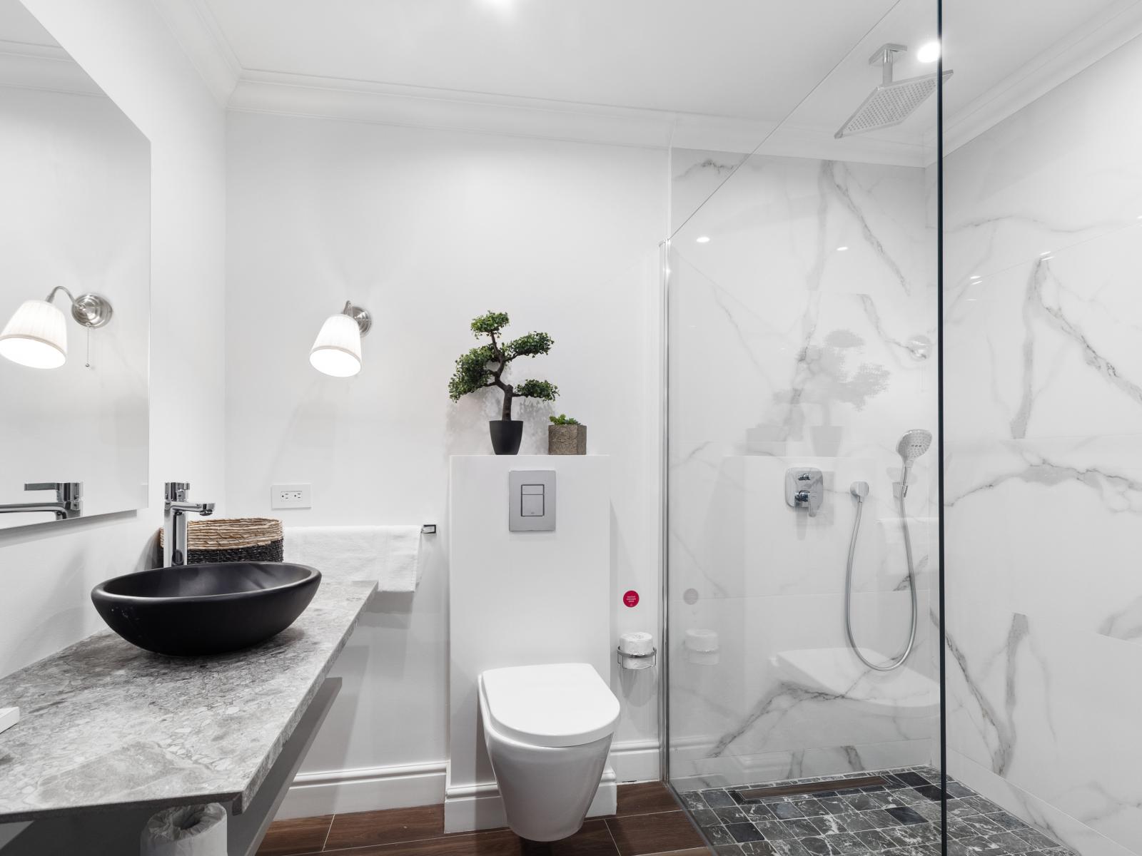 Bathroom two boasts a modern design and a generously spacious shower adorned with sleek marble tiles.