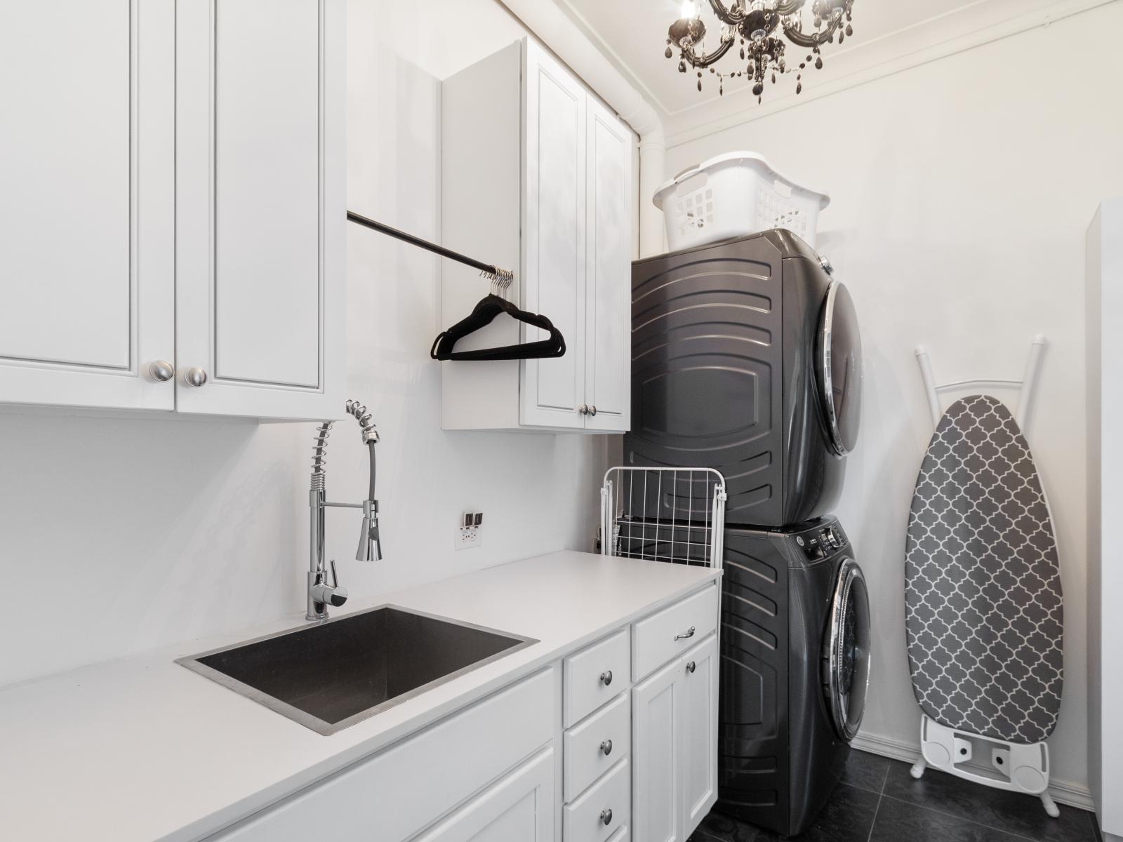 A well-equipped laundry room complete with a washer, dryer, ironing board, and iron, providing all the essentials for your laundry needs.