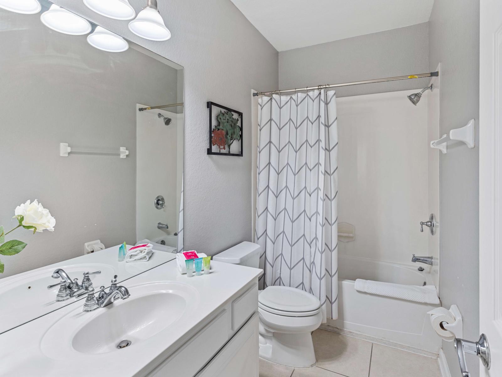 - Exclusive bathroom of the townhouse in Orlando Florida - Effortlessly stylish vanity and chic accessories - Large size wall mirror - Spacious bathtub and shower combo area with sliding curtains - Neat and clean cozy toilet seat