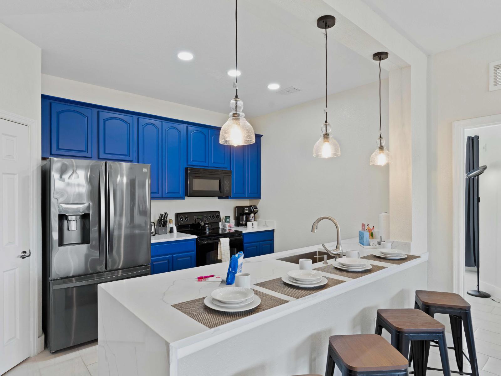 Well-organized kitchen of the condo in Orlando - Beautiful blue and white themed fully equipped kitchen  - Availability of high chairs at the breakfast bar with focus lamps - Plenty of storage space - Completely brightened space