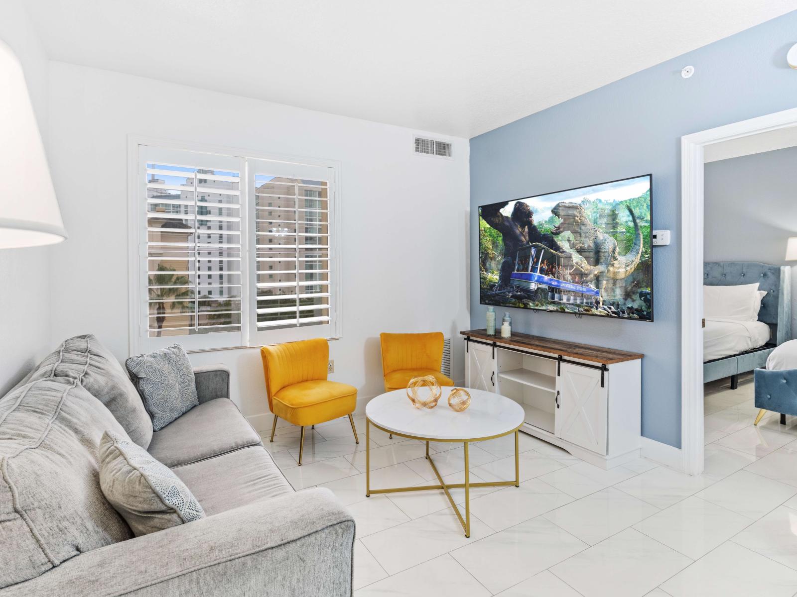 Living room with large smart TV, sleeper sofa and kitchen