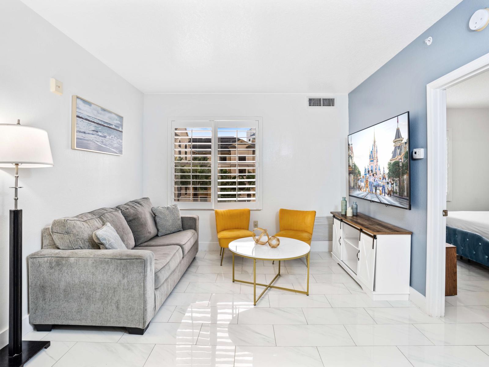 Living room with large smart TV, sleeper sofa and kitchen