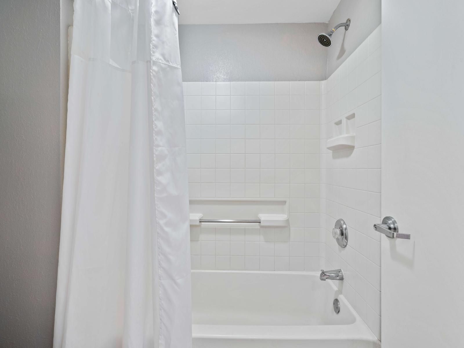 Elegant bathroom of the condo in Orlando Florida - Bathtub and a shower combo with sliding curtain - Well-designed space with a focus on both aesthetics and functionality - Thoughtfully chosen fixtures