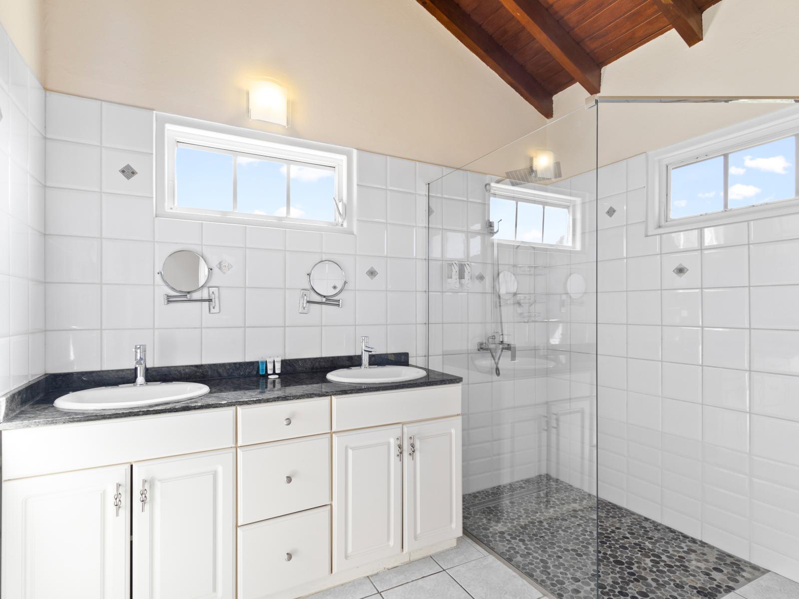 Polished Bathroom of the home in Noord Aruba - Chic design featuring a sleek vanity and upscale lighting - Functional yet glamorous, with thoughtfully chosen fixtures - Seamless design featuring a glass-enclosed shower for a modern touch