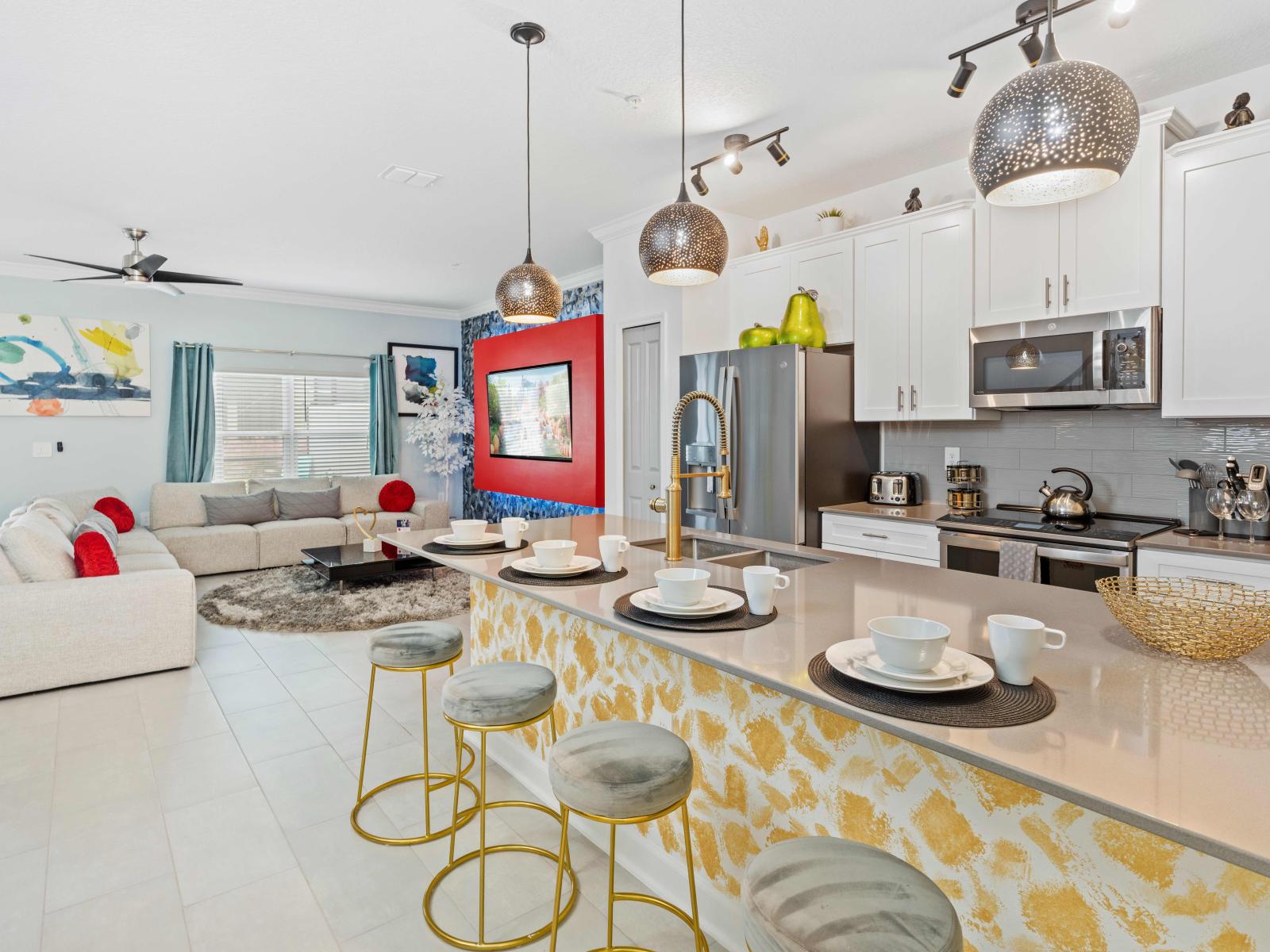 Stylish open concept kitchen with good lighting fronting a countertop table with chairs