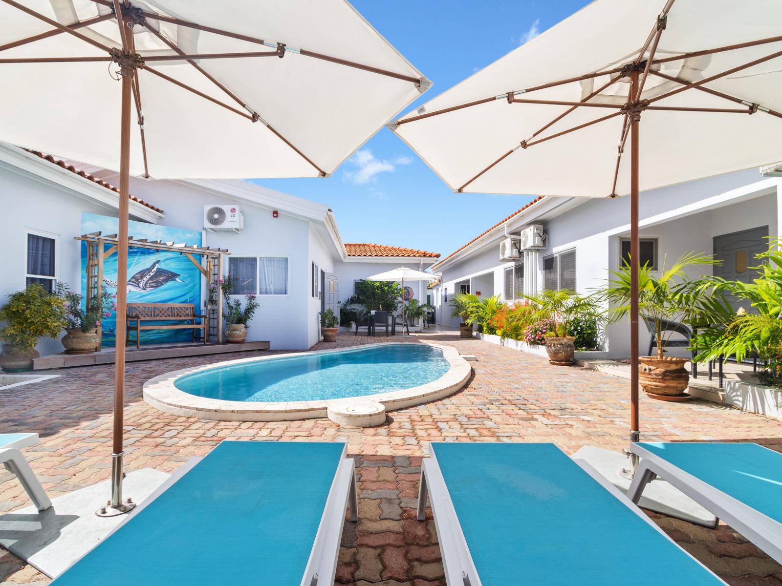 Splendid Shared Pool of the 2BR condo in Noord Aruba - Comfortable lounge chairs for ultimate relaxation - Immerse yourself in the cool elegance of our pool - Experience ultimate relaxation in our poolside paradise